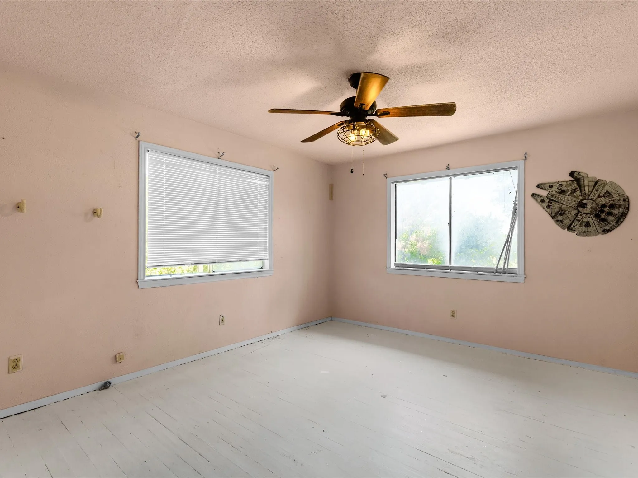 Room featuring painted wood-finish flooring and two windows with blinds