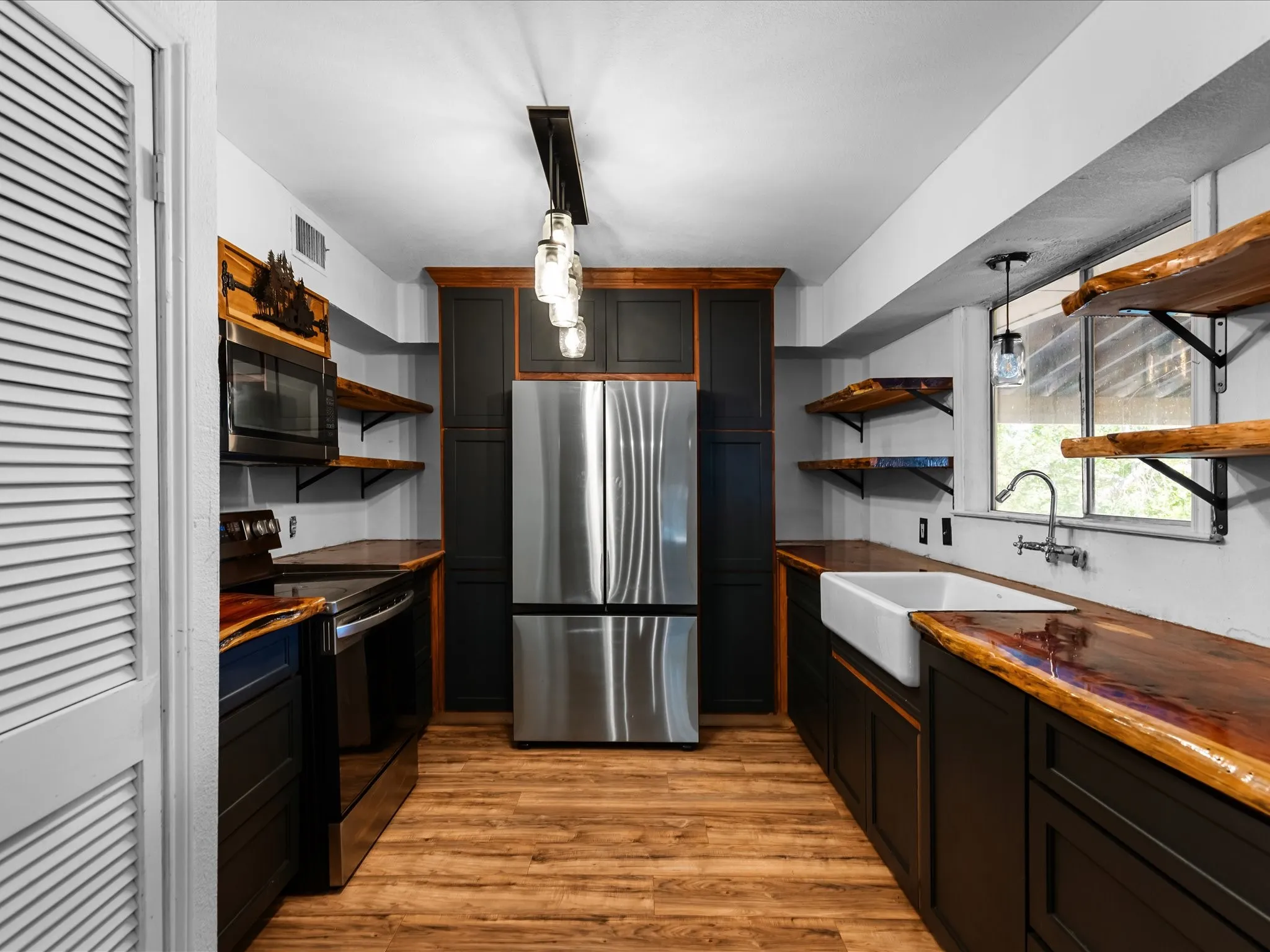 Galley kitchen featuring wood-finish flooring, dark cabinetry, and live-edge wood countertops