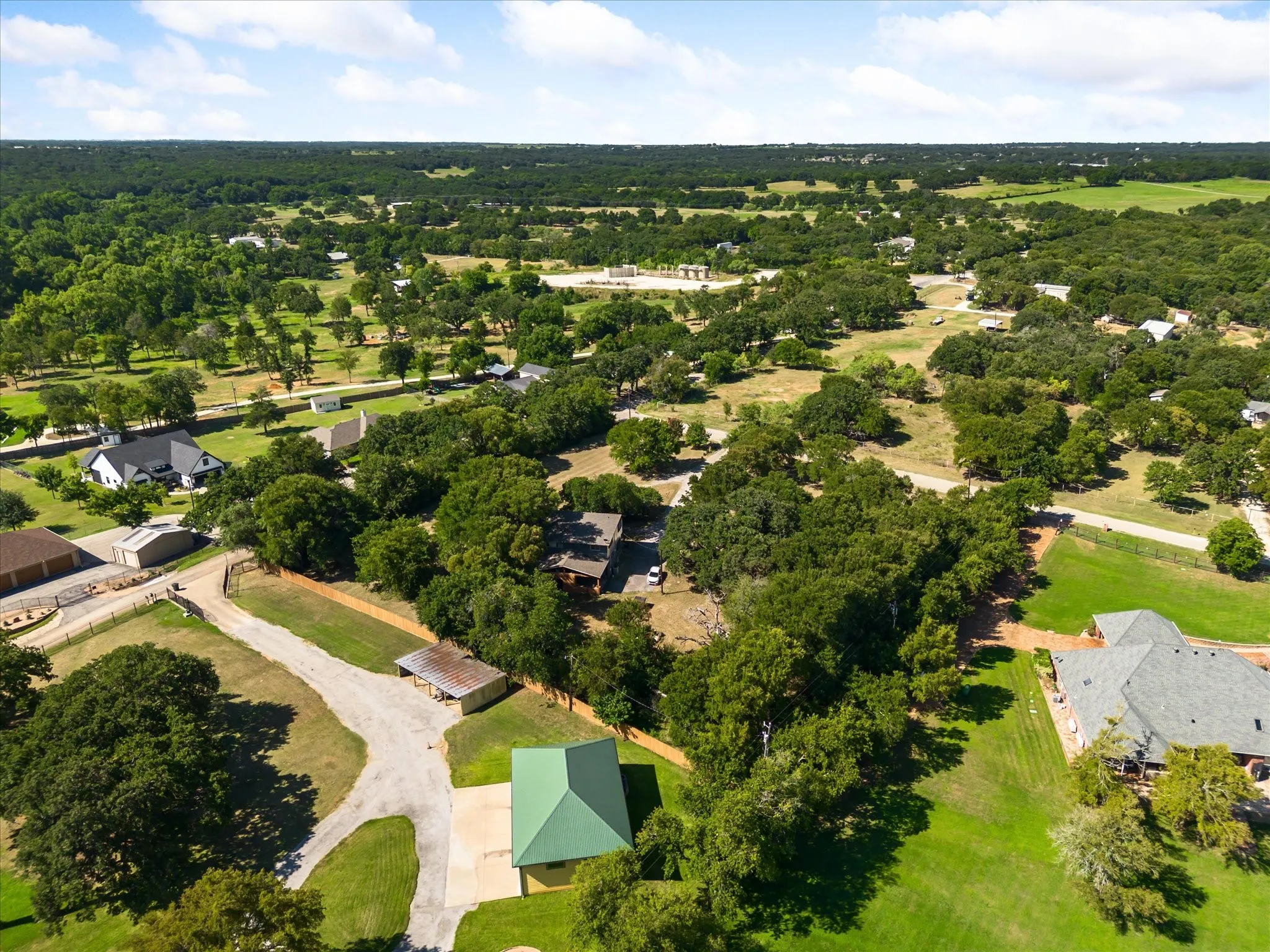 Expansive property featuring a green metal roof structure and a gravel driveway