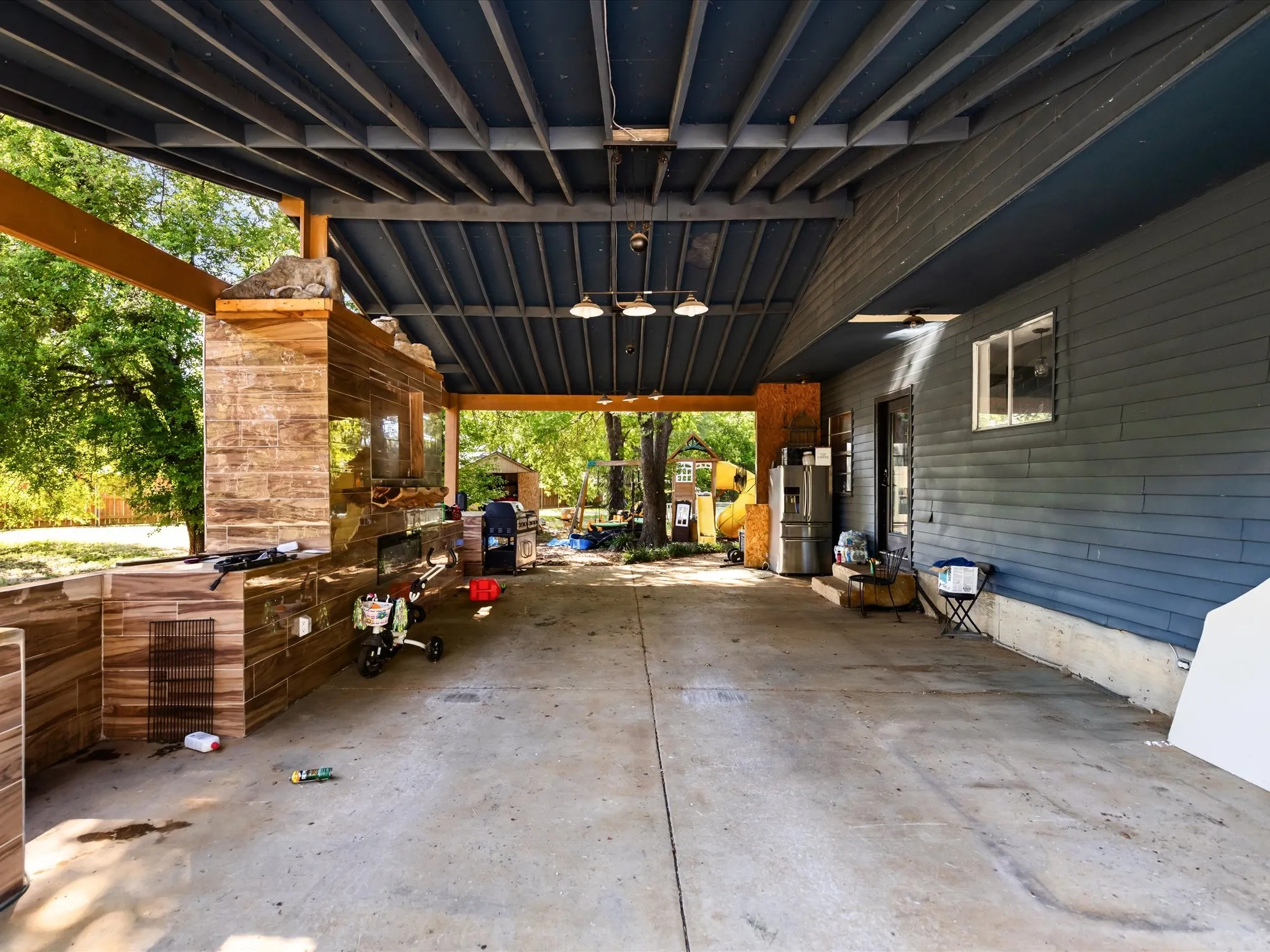 Covered outdoor area featuring a concrete surface, exposed ceiling joists, and recessed lighting