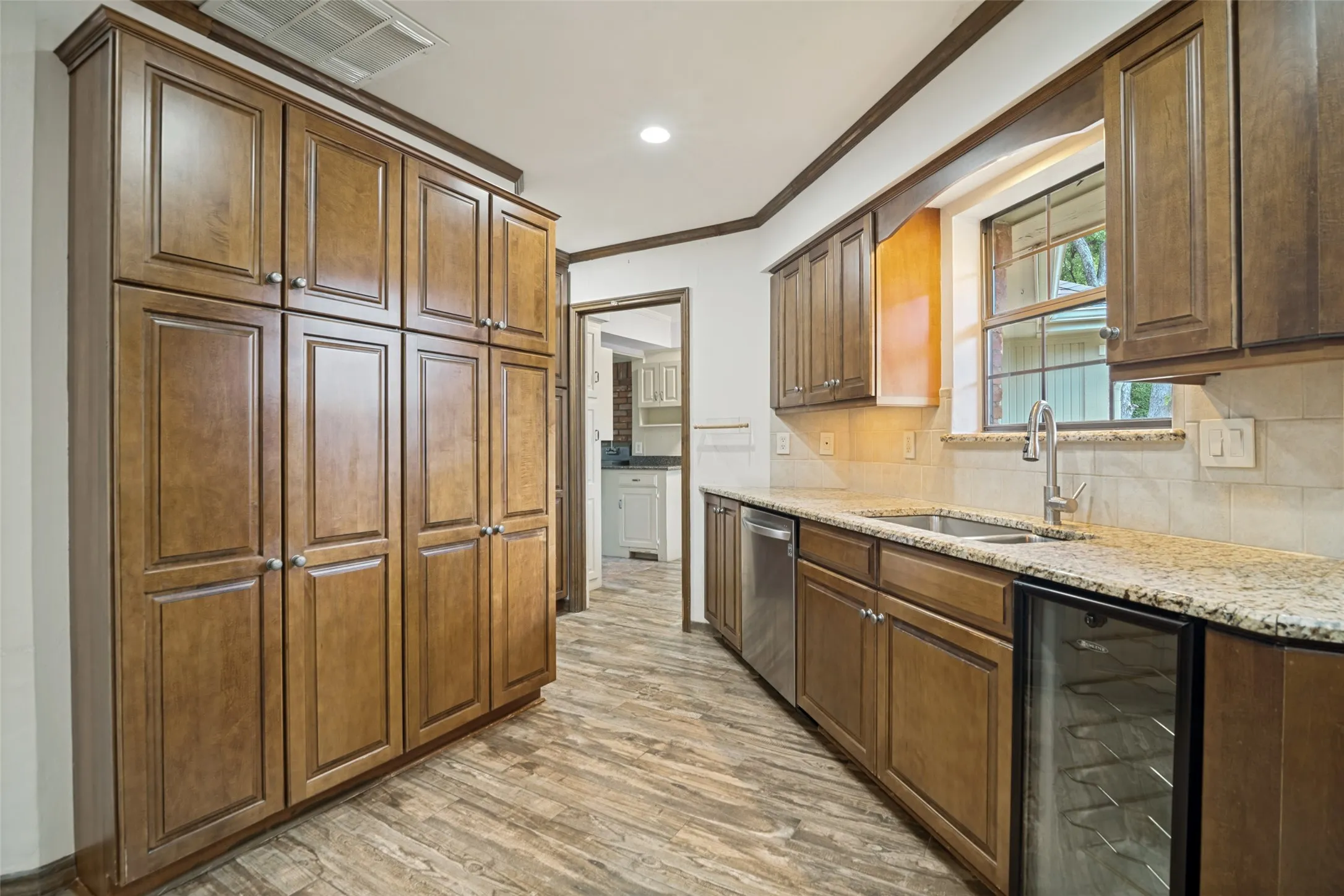 A wall of cabinetry behind the sink, the angle of the photo narrows the view, there is lots of room! Looking towards the utility room.