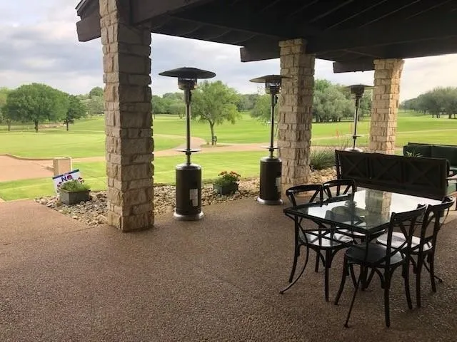 Expansive covered patio featuring stone columns and a textured concrete surface