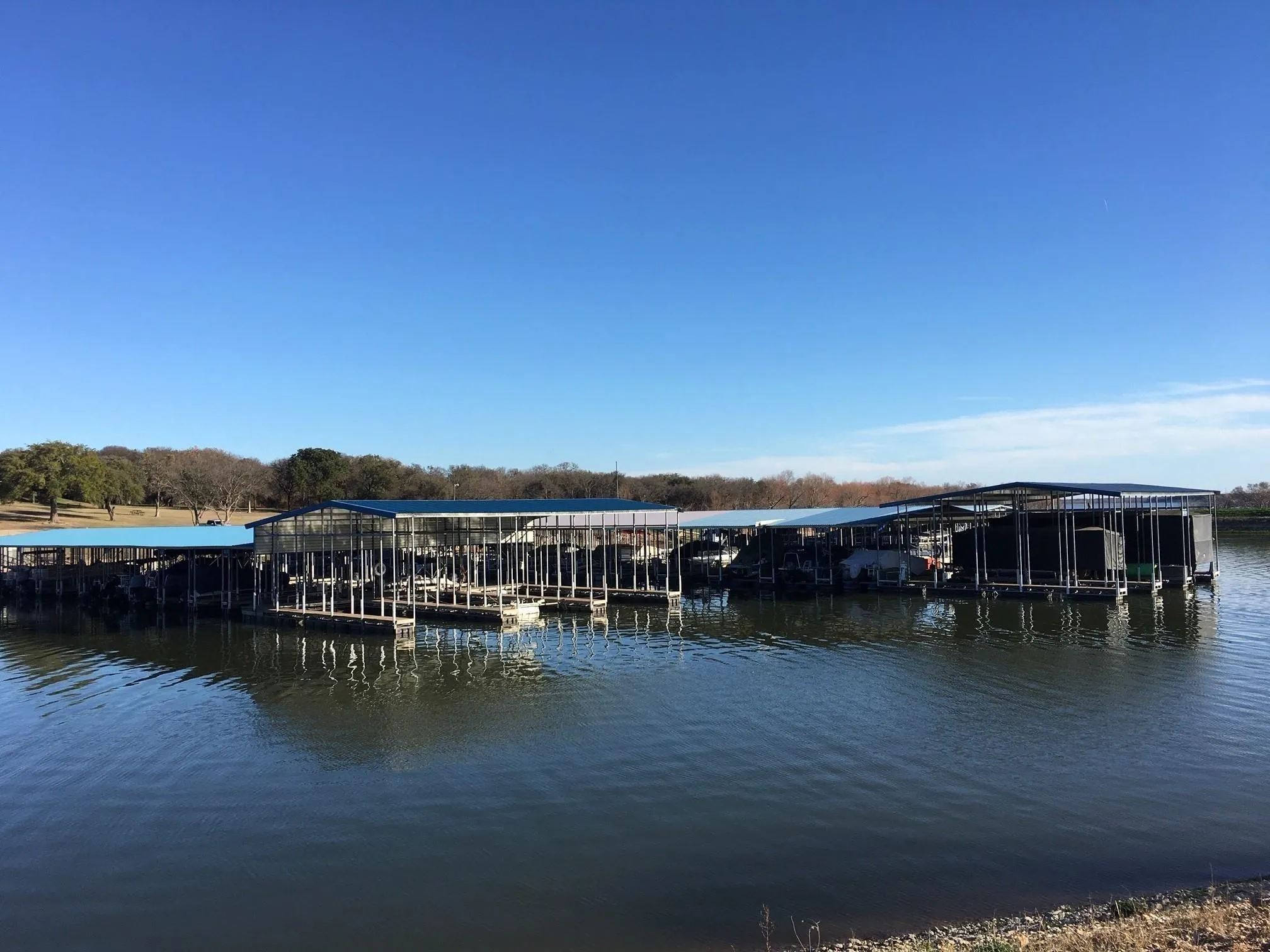 Large boat dock featuring multiple slips with covered roofs, supported by sturdy pilings