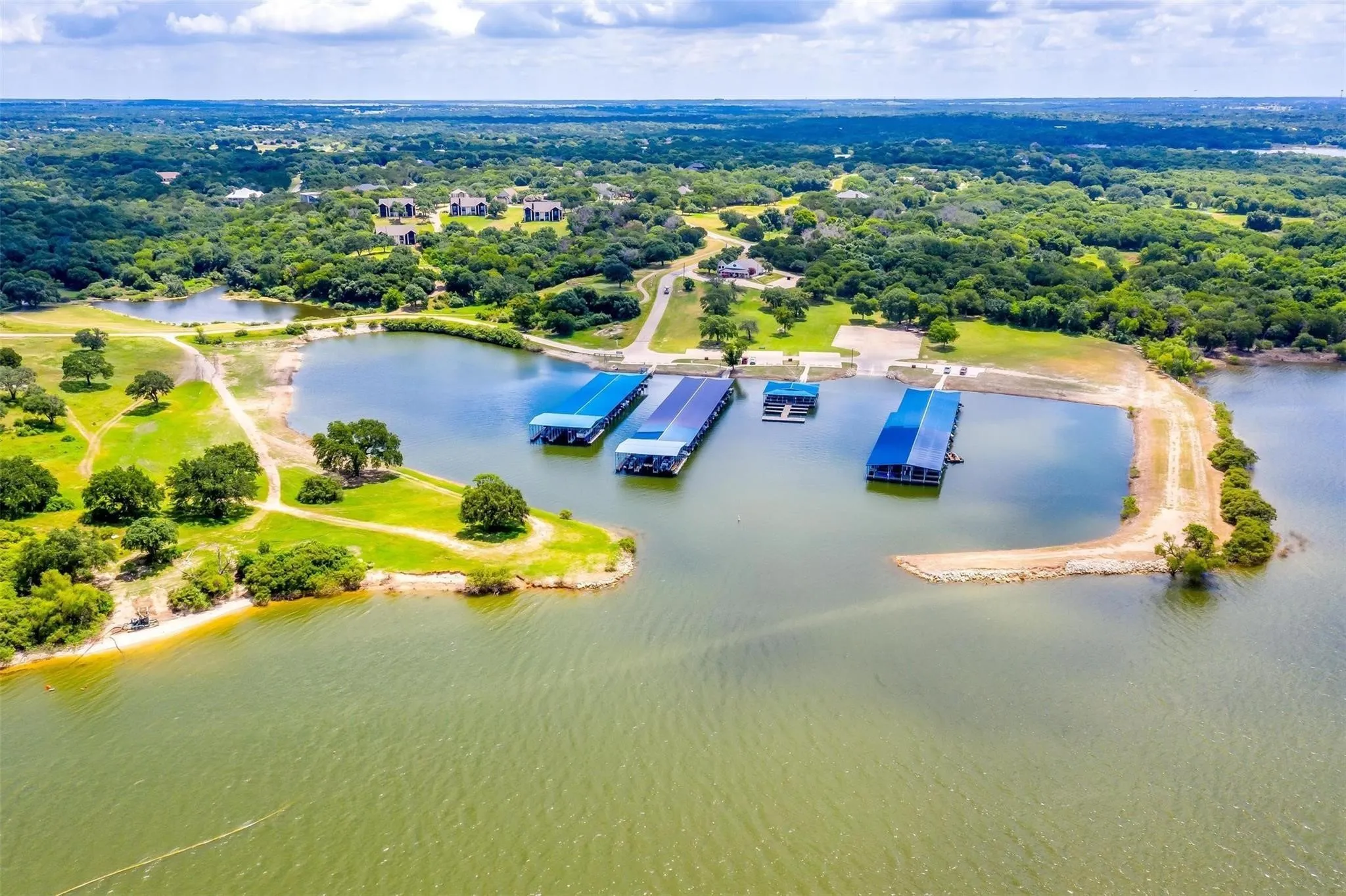 Expansive lakefront property featuring multiple covered boat docks, a boat ramp, and direct water access