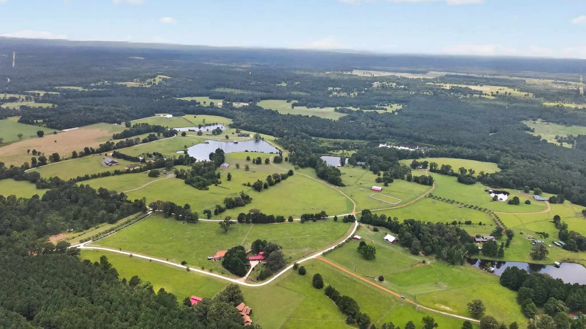 Expansive aerial view of Kellyville Ranch, featuring lush pastures, mature hardwoods, outstanding equestrian community.