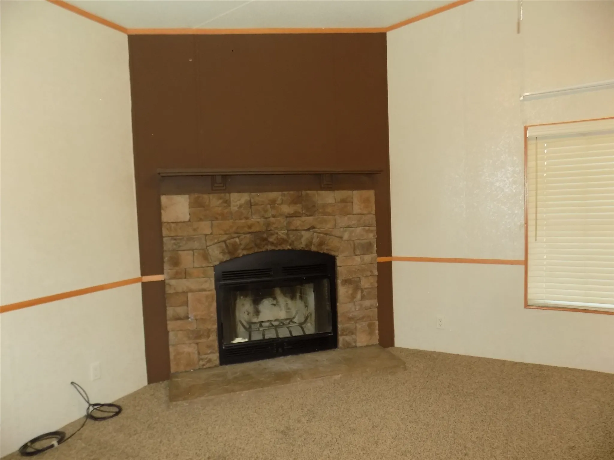 Large fireplace in corner of den, making the room very warm and welcoming. The room has multiple windows and ceiling fans with lights.  Lovely, comfortable room.