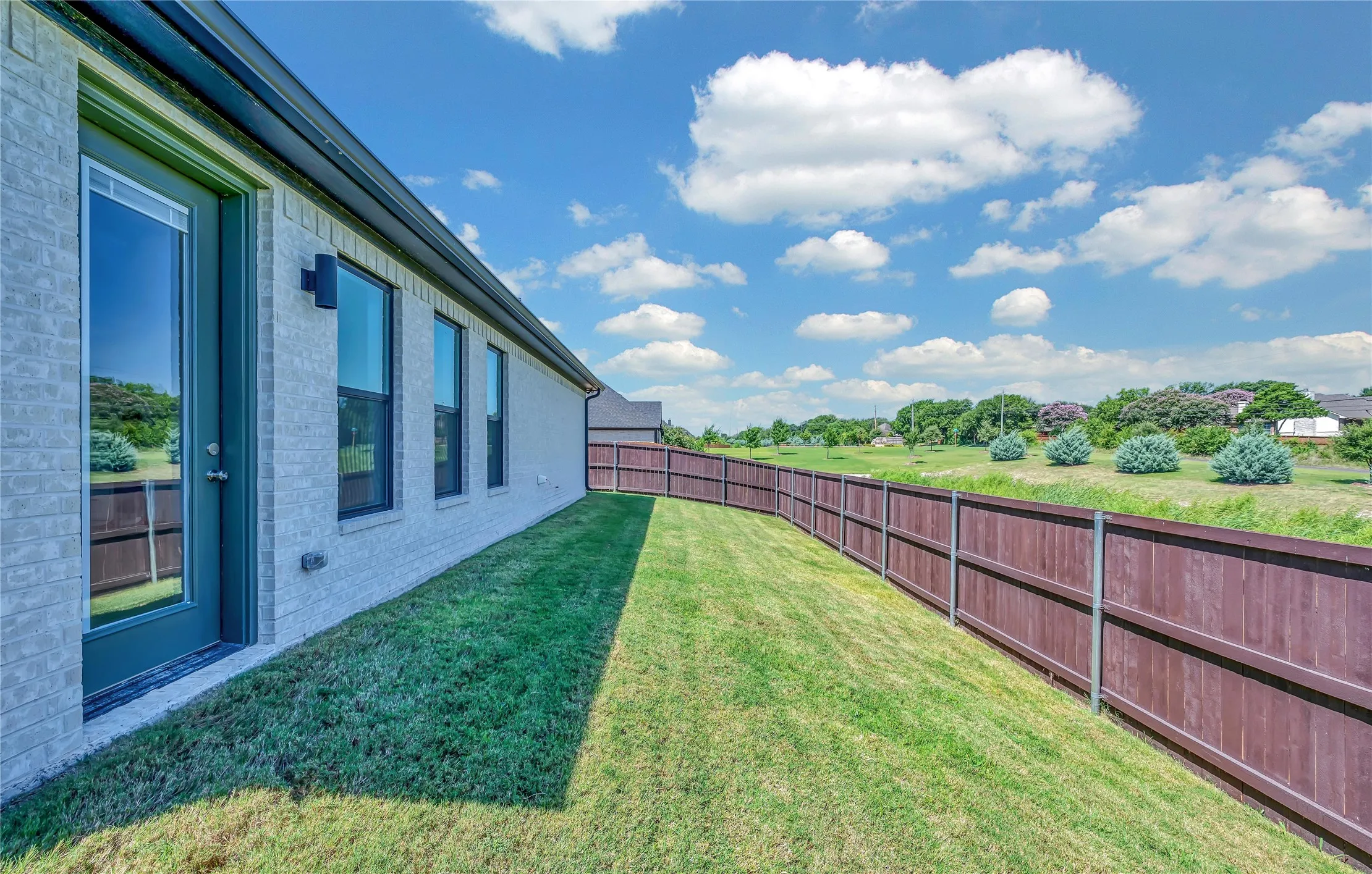 Expansive green space featuring a wood privacy fence and mature landscaping