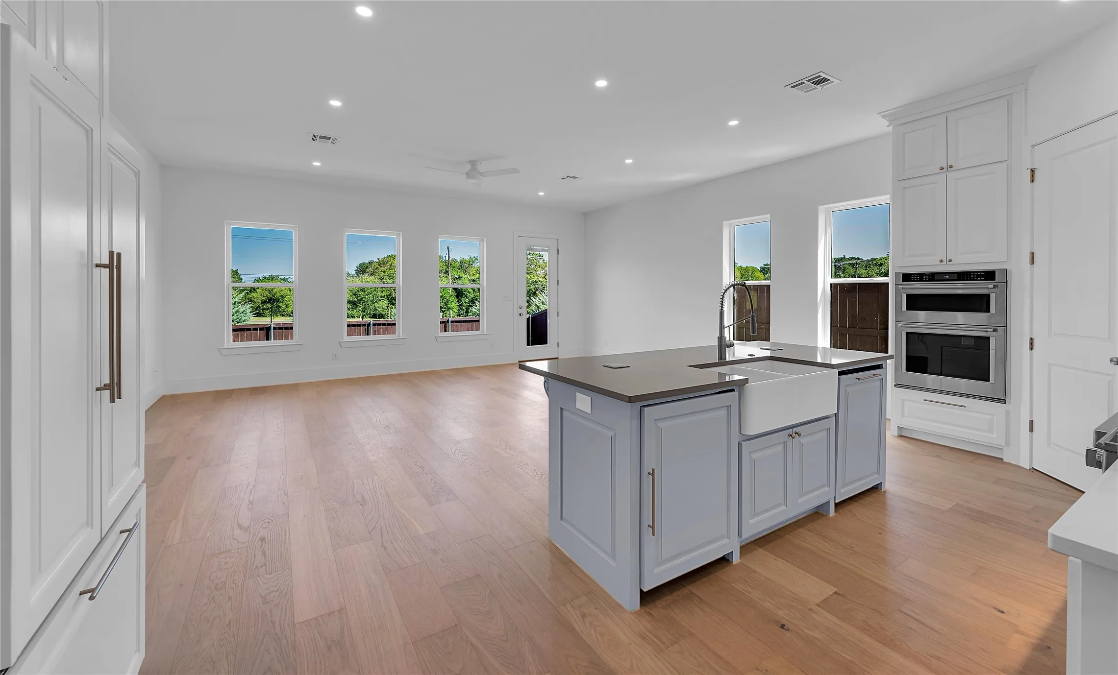 Spacious room featuring wood-finish flooring, recessed lighting, and multiple windows