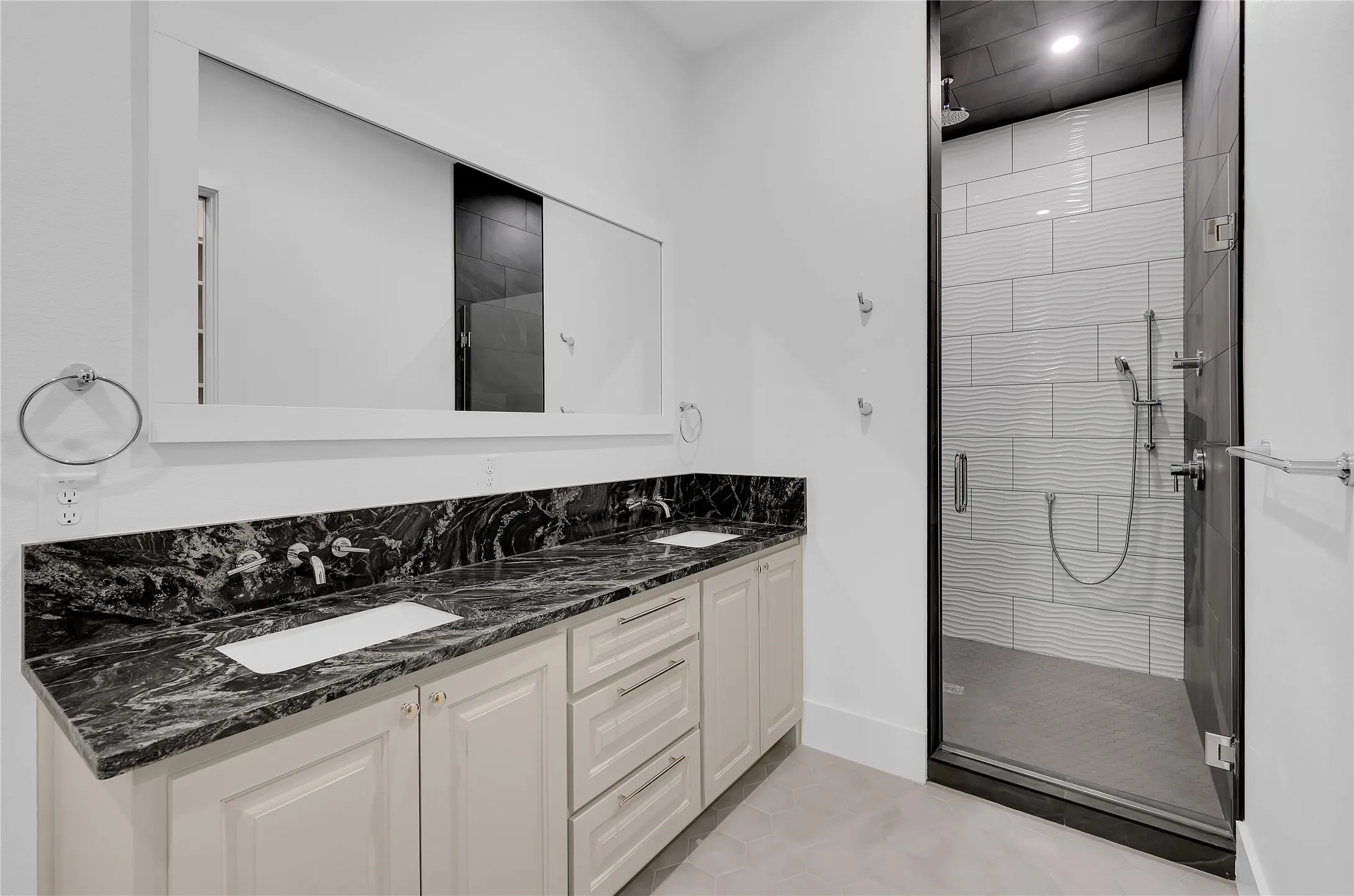 Spacious bathroom featuring a double vanity with stone countertops, undermount sinks, and wall-mounted faucets