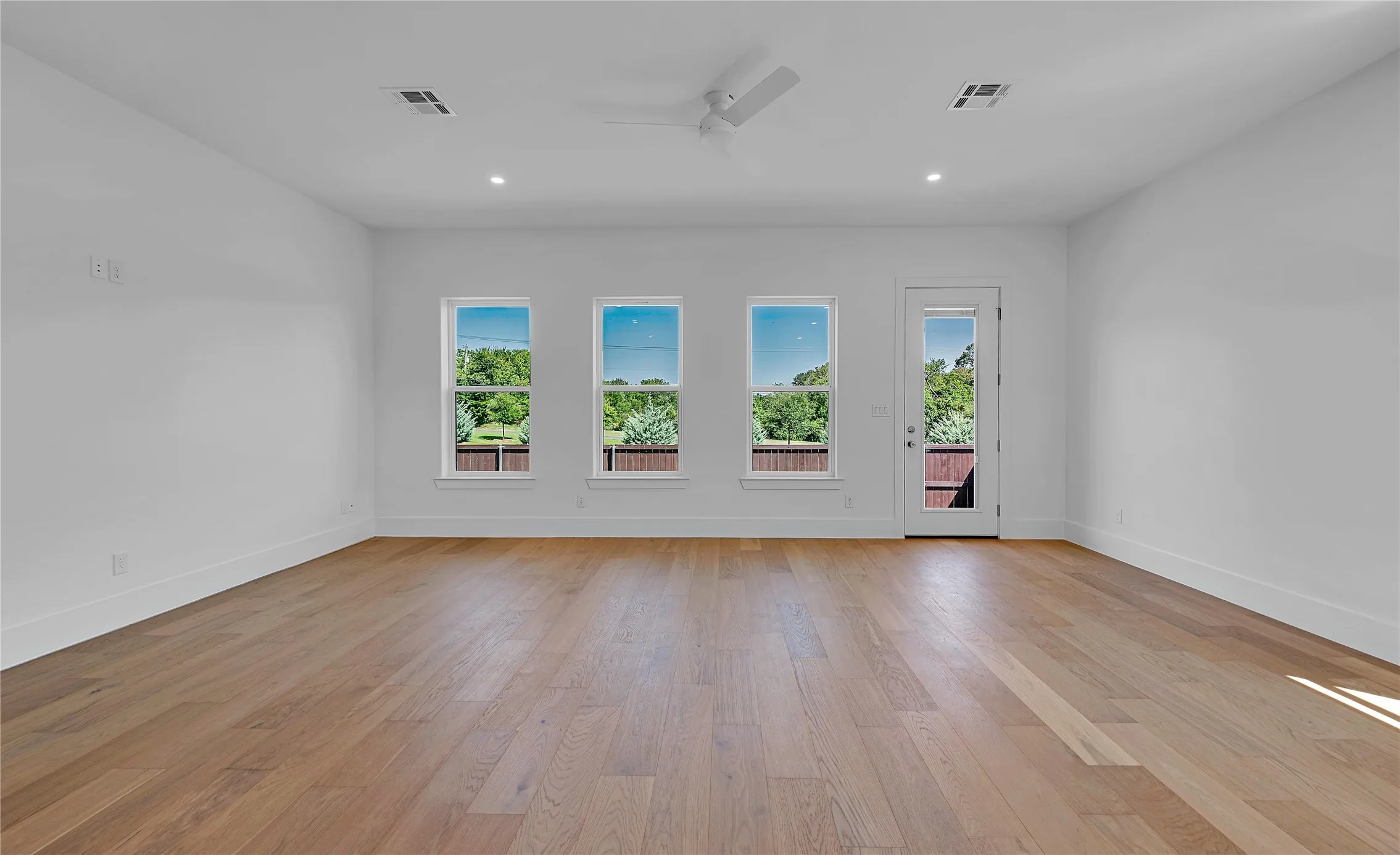 Expansive room featuring wood-finish flooring, recessed lighting, and a modern ceiling fan