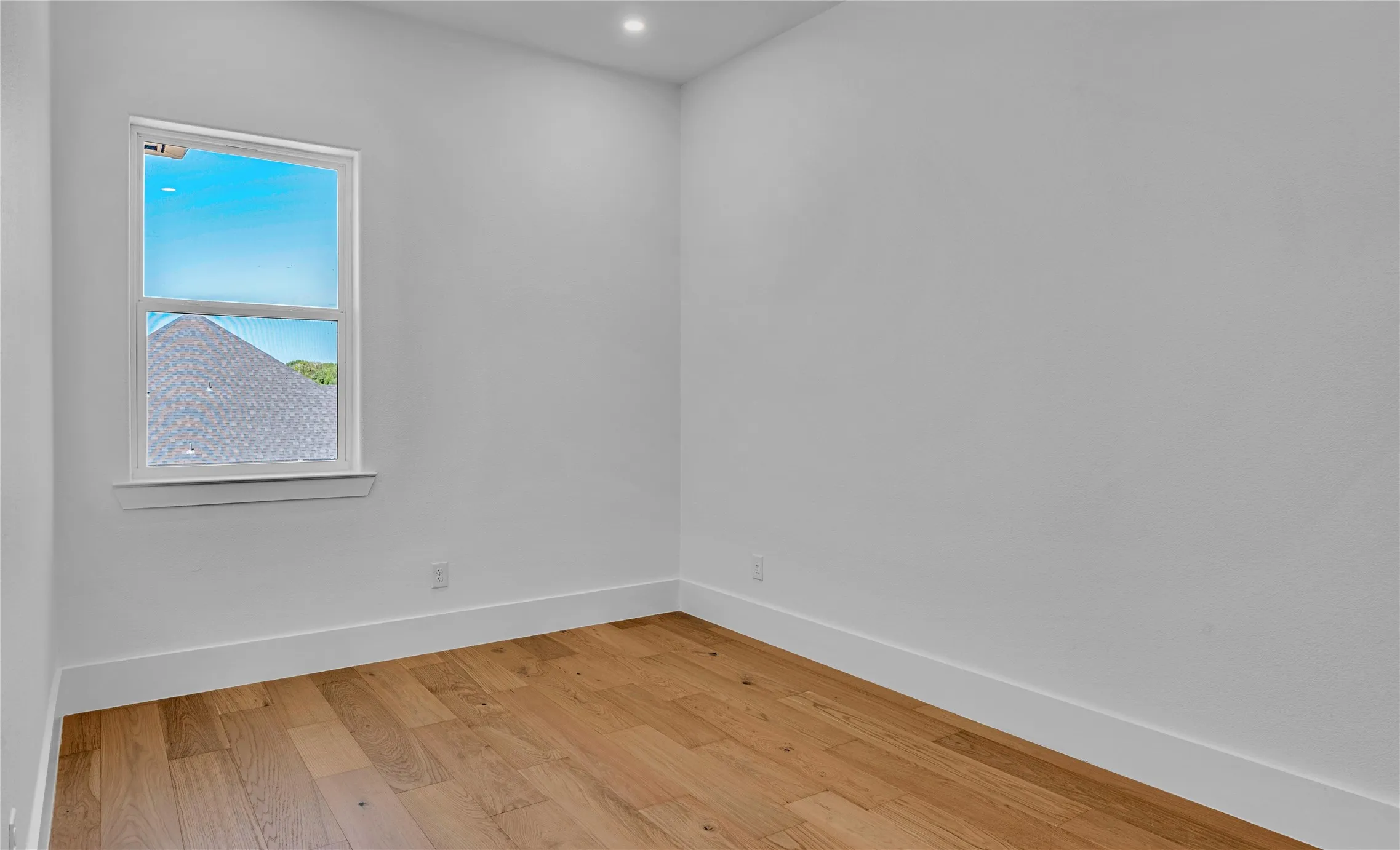 Bright interior space featuring wood-finish flooring, white walls, and a recessed ceiling light