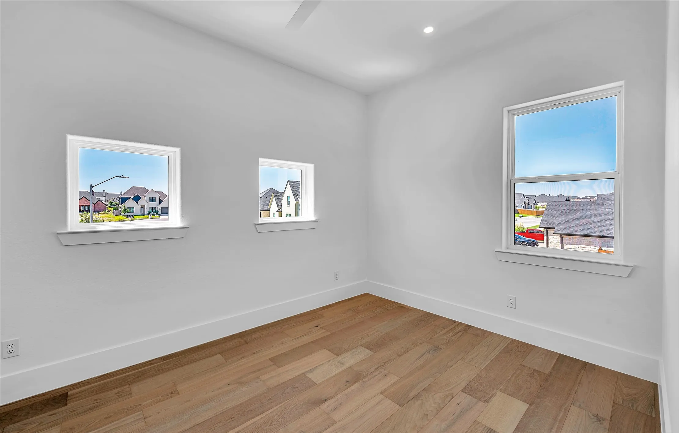 Room featuring wood-finish flooring, white baseboards, and bright white walls