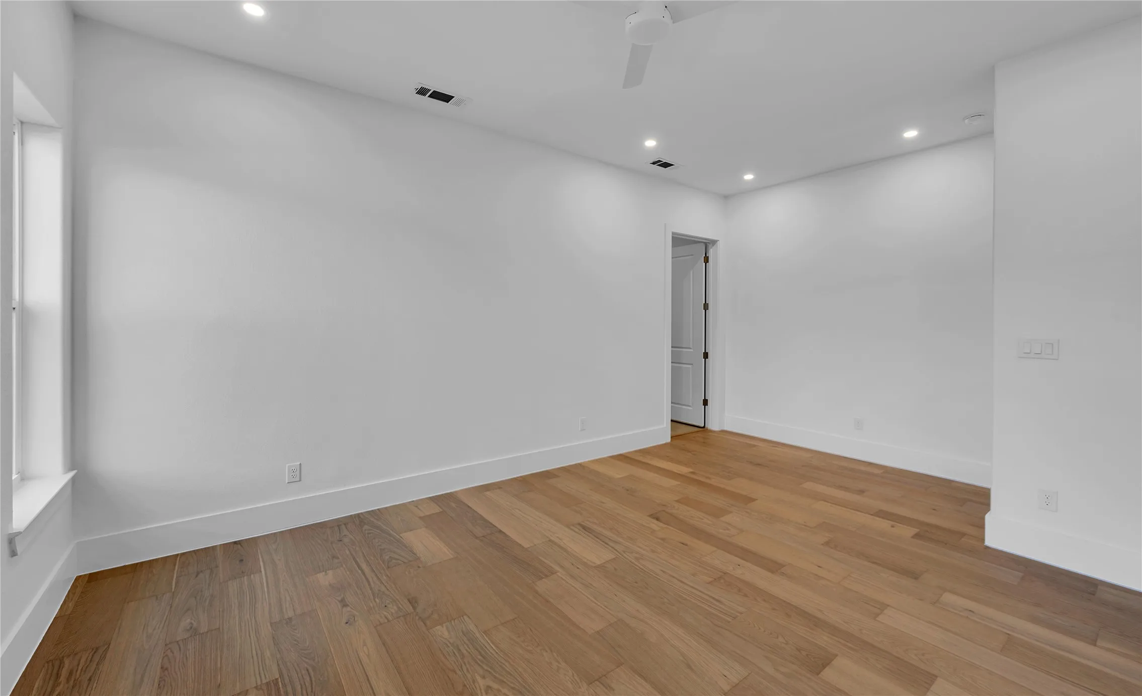 Spacious room featuring wood-finish flooring, recessed lighting, and a ceiling fan