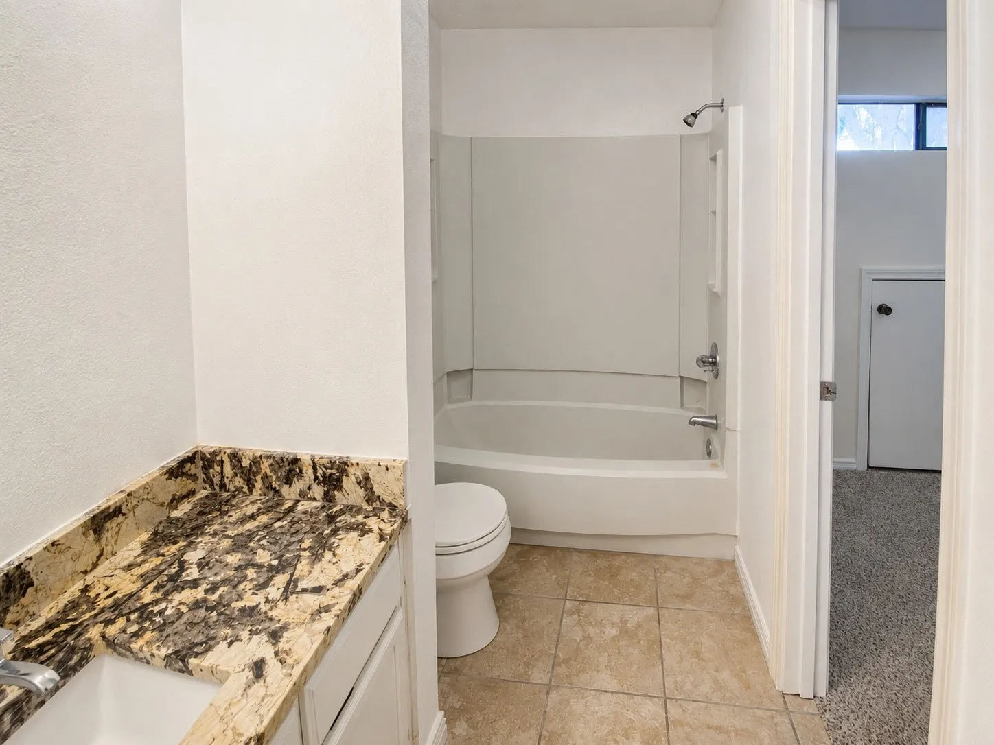 Bathroom featuring a vanity with a patterned stone countertop, an integrated sink, and white cabinetry