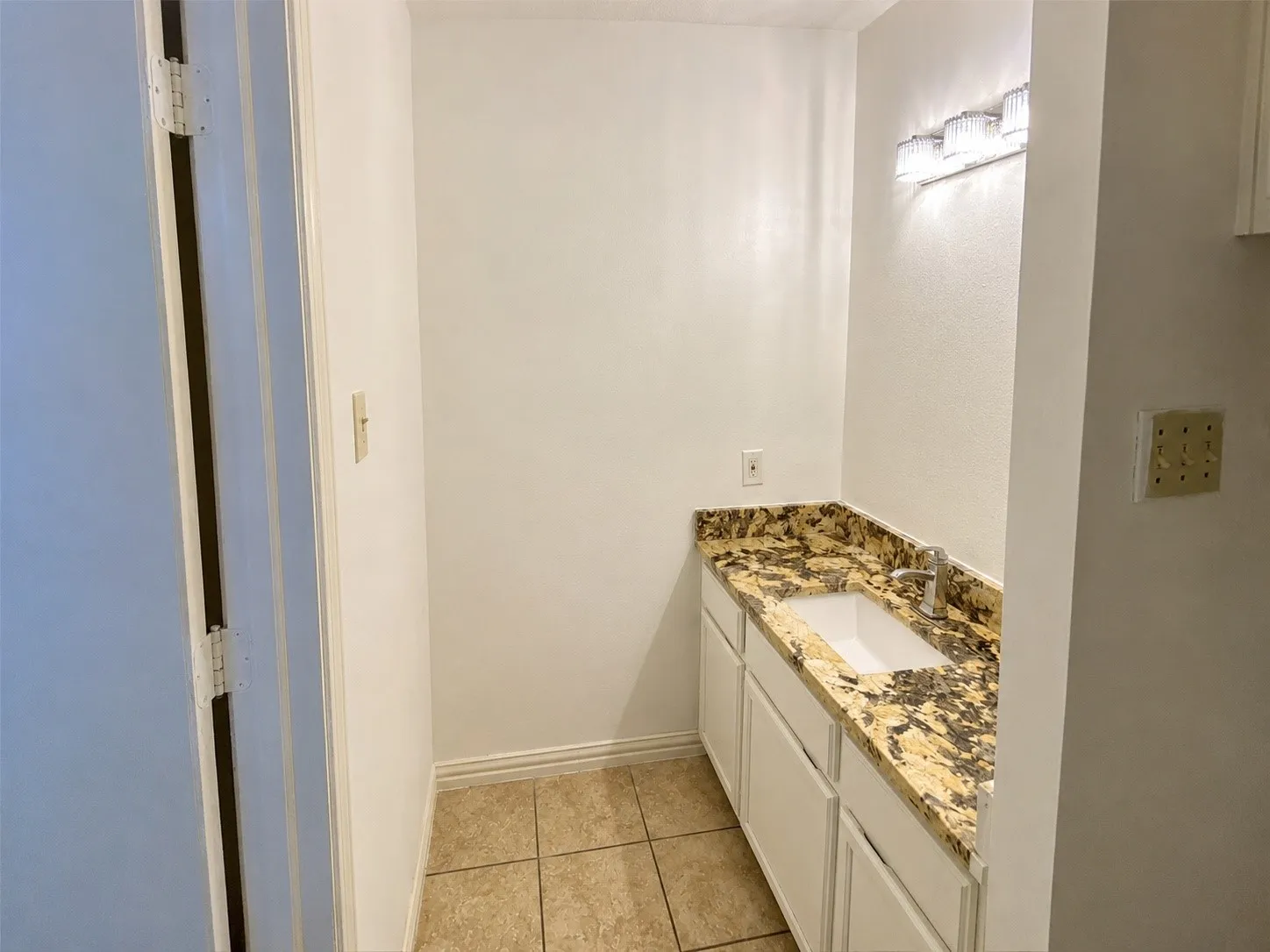 Vanity area featuring a gold and brown patterned countertop, undermount sink, and polished chrome faucet