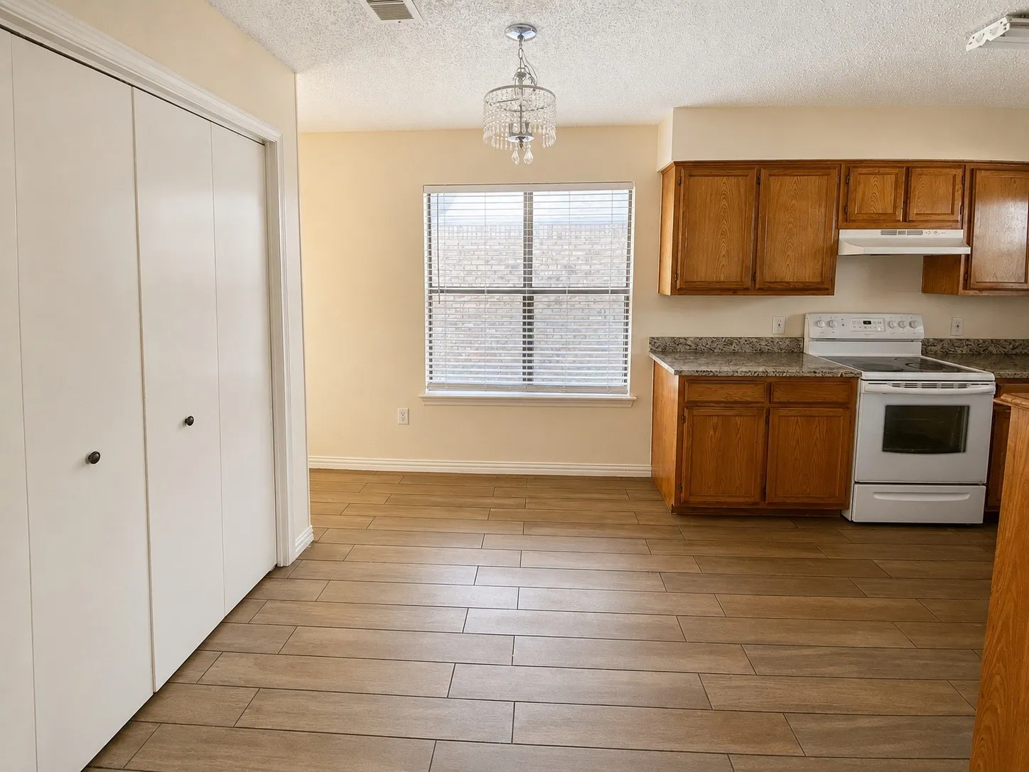 Kitchen space featuring wood-finish flooring, oak cabinetry, and granite-look countertops