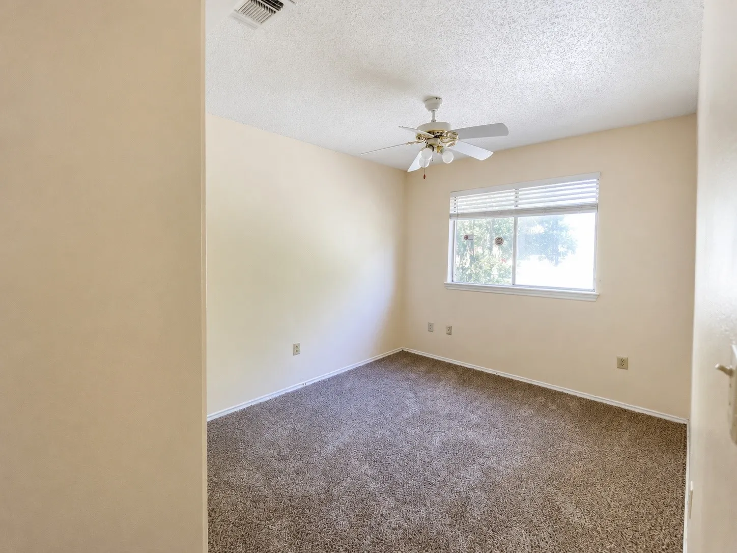 Carpeted room featuring a window with horizontal blinds, a ceiling fan with integrated lighting, and neutral-toned walls