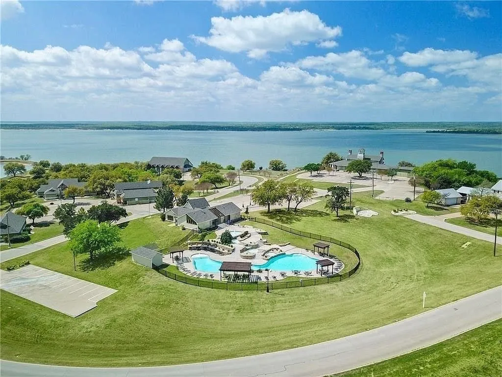 Expansive lakefront community featuring a large, irregularly shaped swimming pool with integrated seating, surrounded by a black metal fence