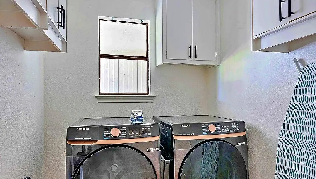 Dedicated utility space featuring a window, built-in cabinetry with black hardware, and an open storage shelf