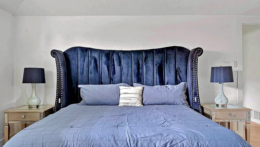 Bedroom featuring a deep blue upholstered headboard with nailhead trim