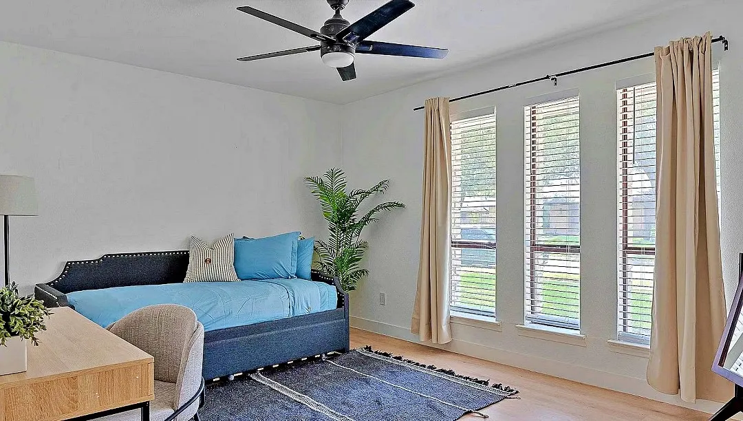 Bright room featuring light wood-finish flooring, white walls, and a ceiling fan with integrated lighting