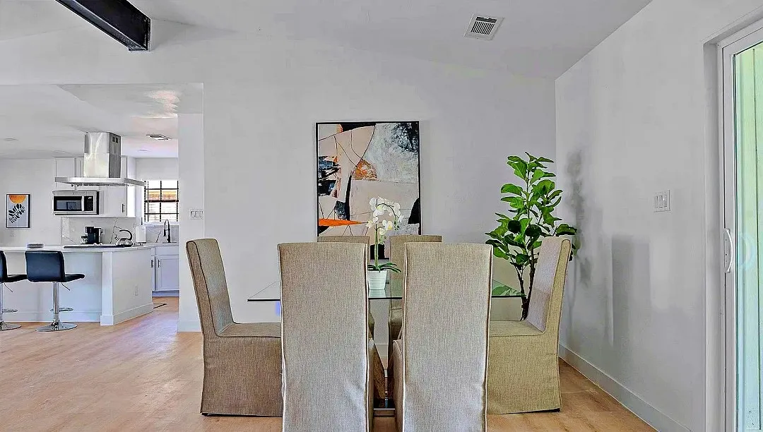 Dining area featuring light wood-finish flooring, white walls, and a vaulted ceiling with exposed beam