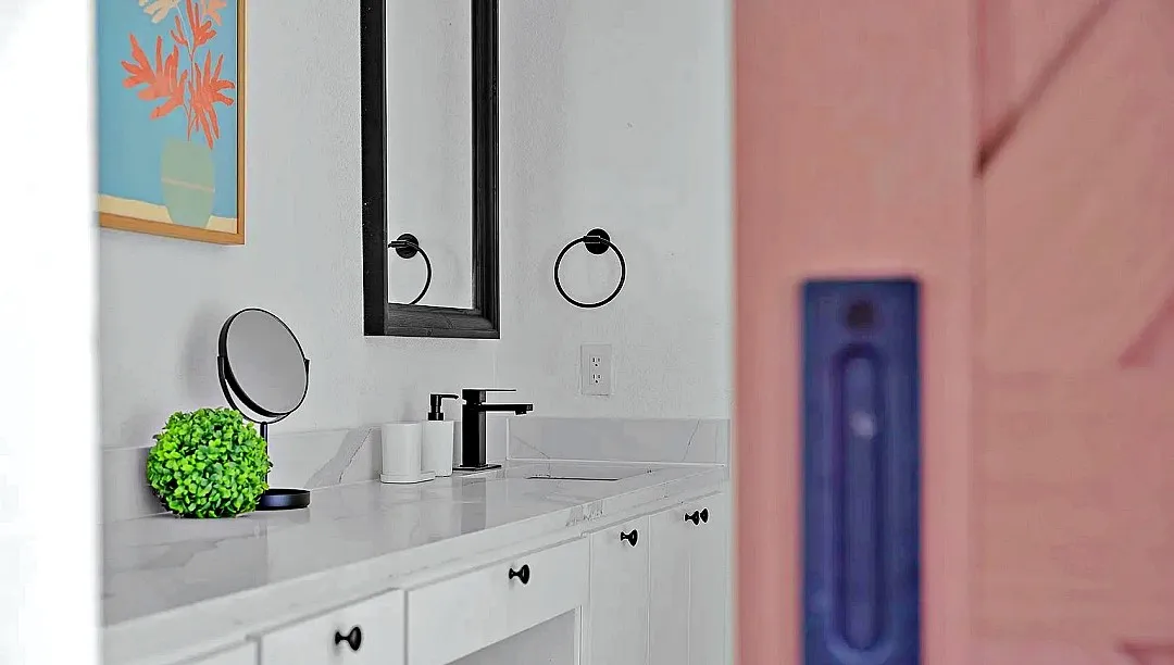 White vanity with a light-toned countertop, under-mount sink, and matte black faucet
