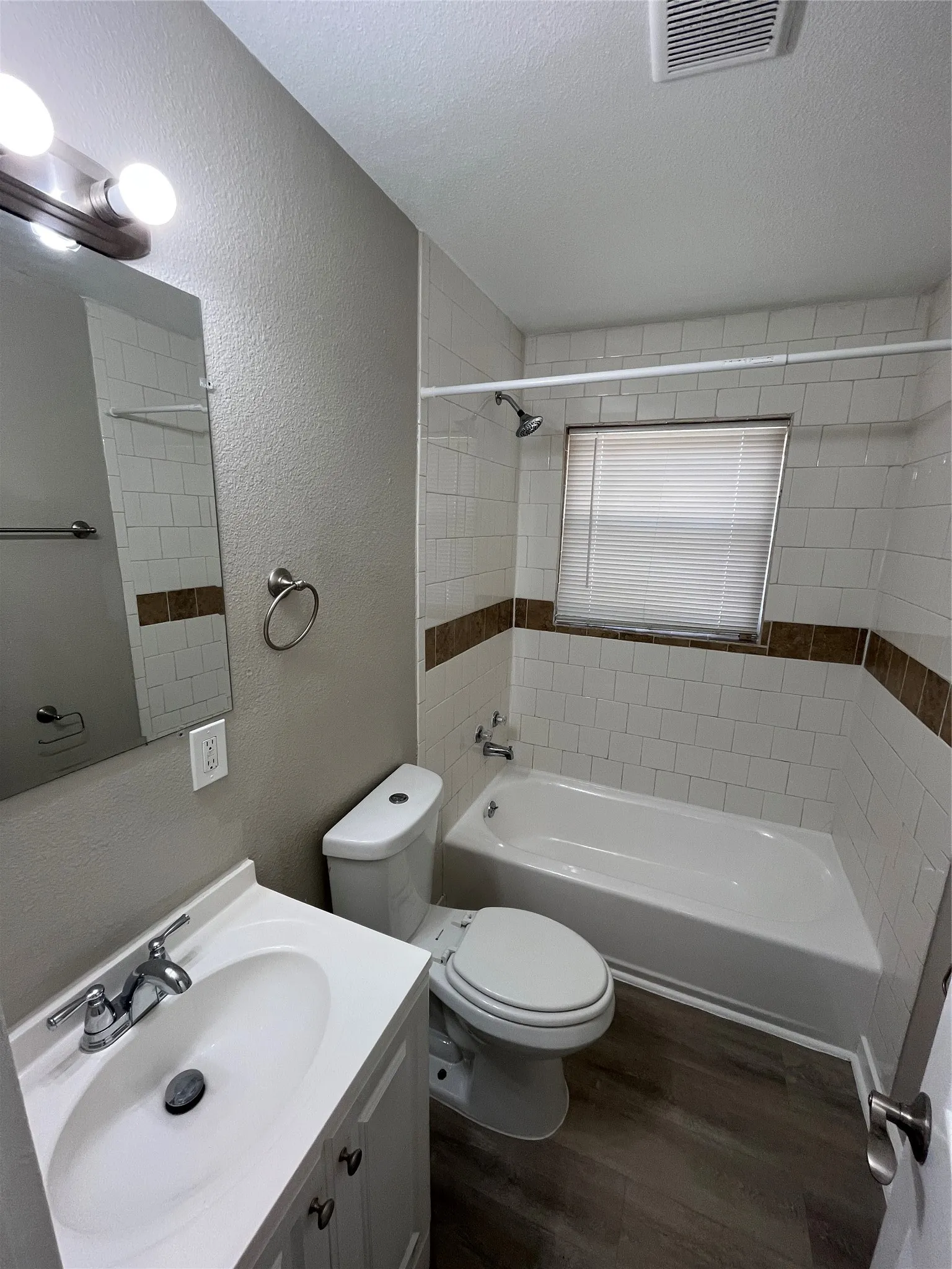 Bathroom featuring a white vanity with a chrome faucet, a rectangular mirror, and a two-bulb vanity light