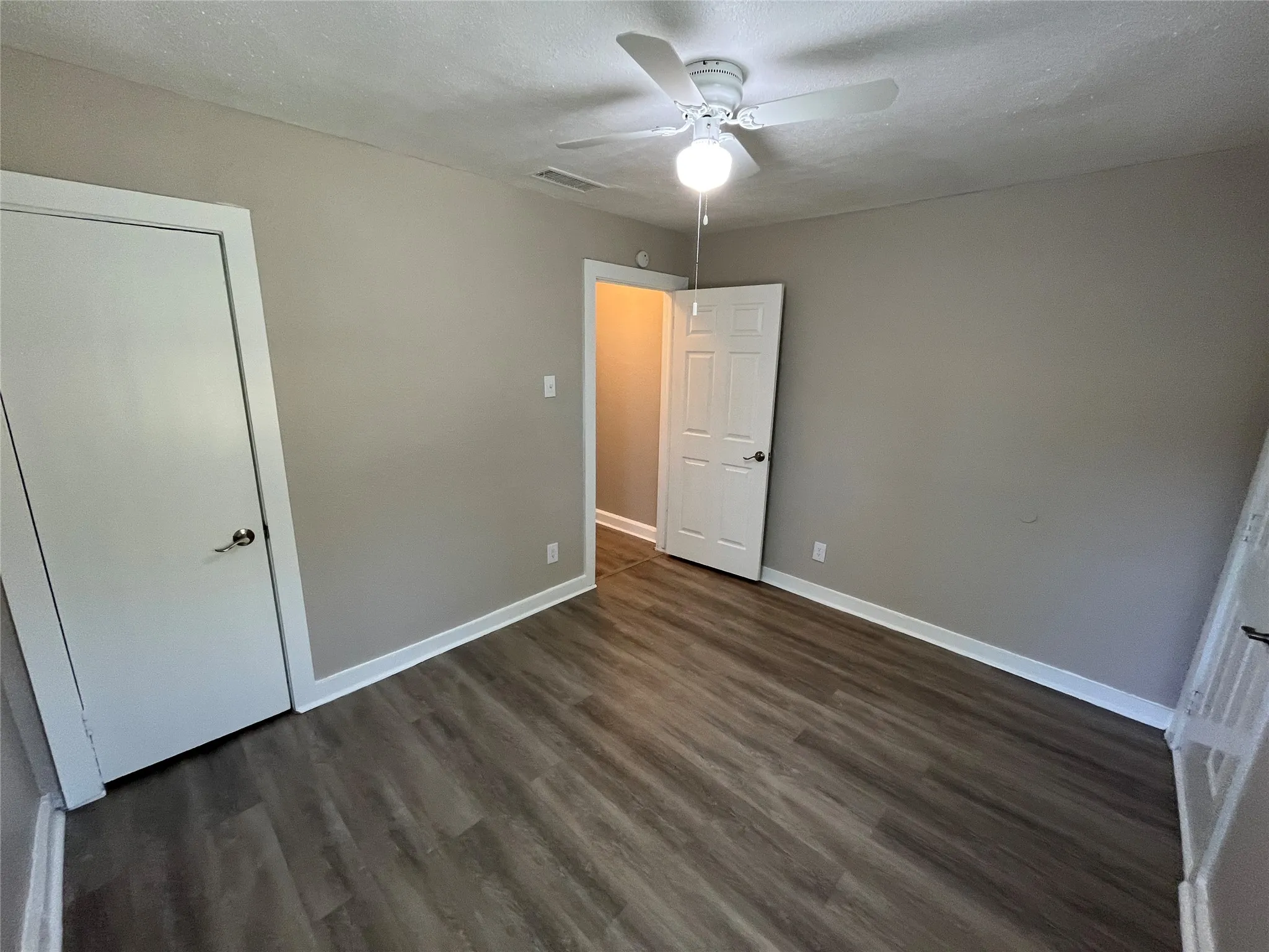 Interior room with wood-finish flooring, light tan wall color, and white trim