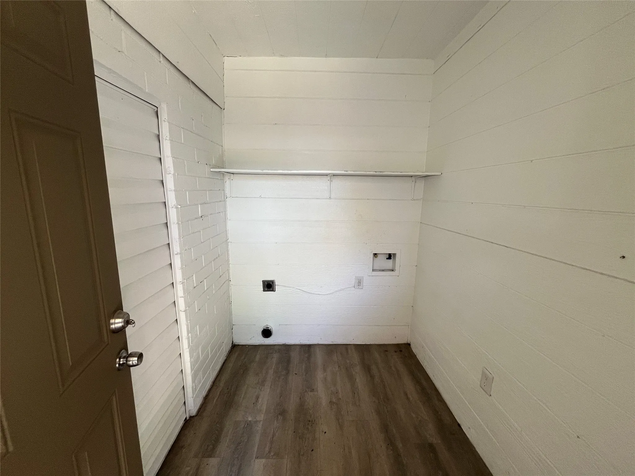 Utility area featuring wood-finish flooring and white shiplap walls
