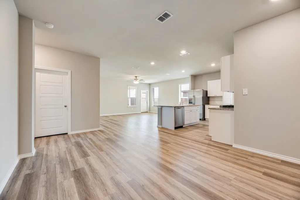 Open-concept living area with wood-finish flooring, recessed lighting, and a neutral color palette