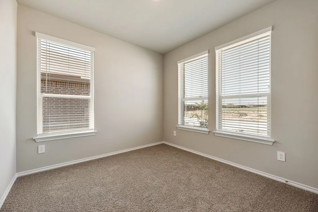 Carpeted room featuring three windows with blinds, light-toned walls, and white baseboards