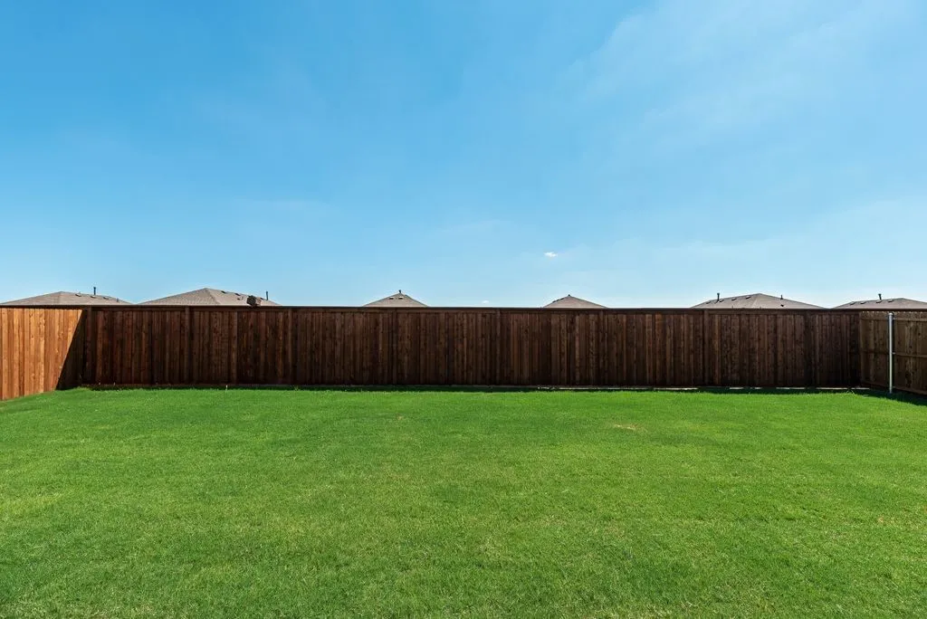 Expansive backyard featuring a lush green lawn and new wood privacy fencing