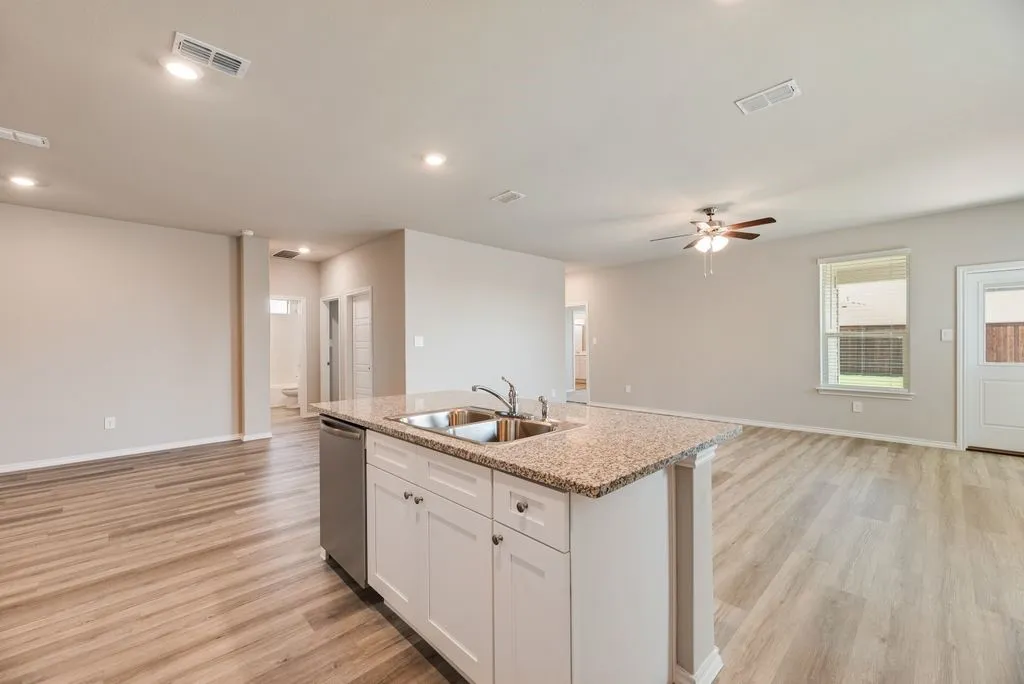 Kitchen island with a double basin sink, stainless steel dishwasher, and granite-style countertop