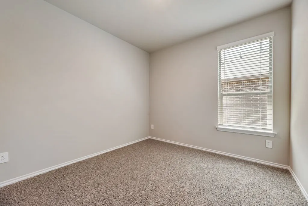 Neutral tone walls, plush carpet flooring, white trim, and a window with blinds