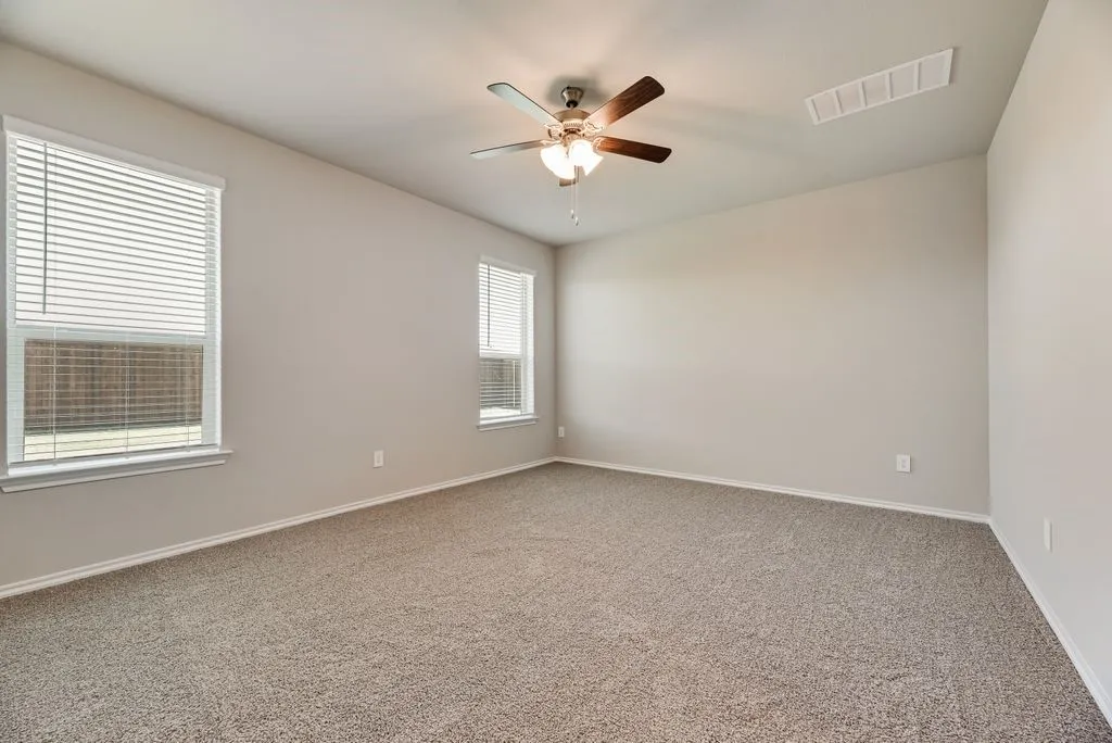 Spacious room featuring neutral carpeting, light-toned walls, and a multi-speed ceiling fan with integrated lighting