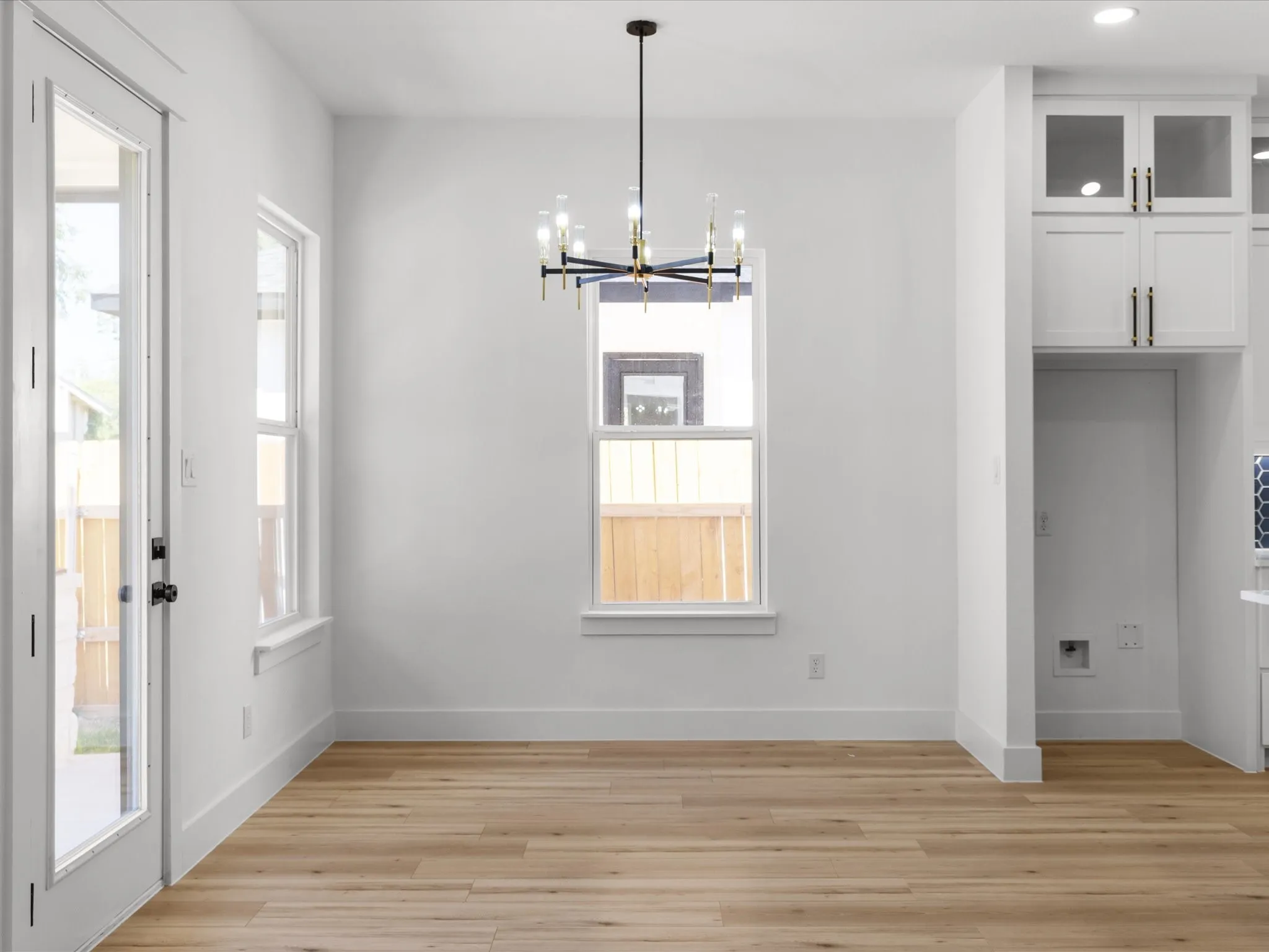 Dining area featuring wood-finish flooring, a contemporary chandelier, two windows, and a glass-paneled exterior door