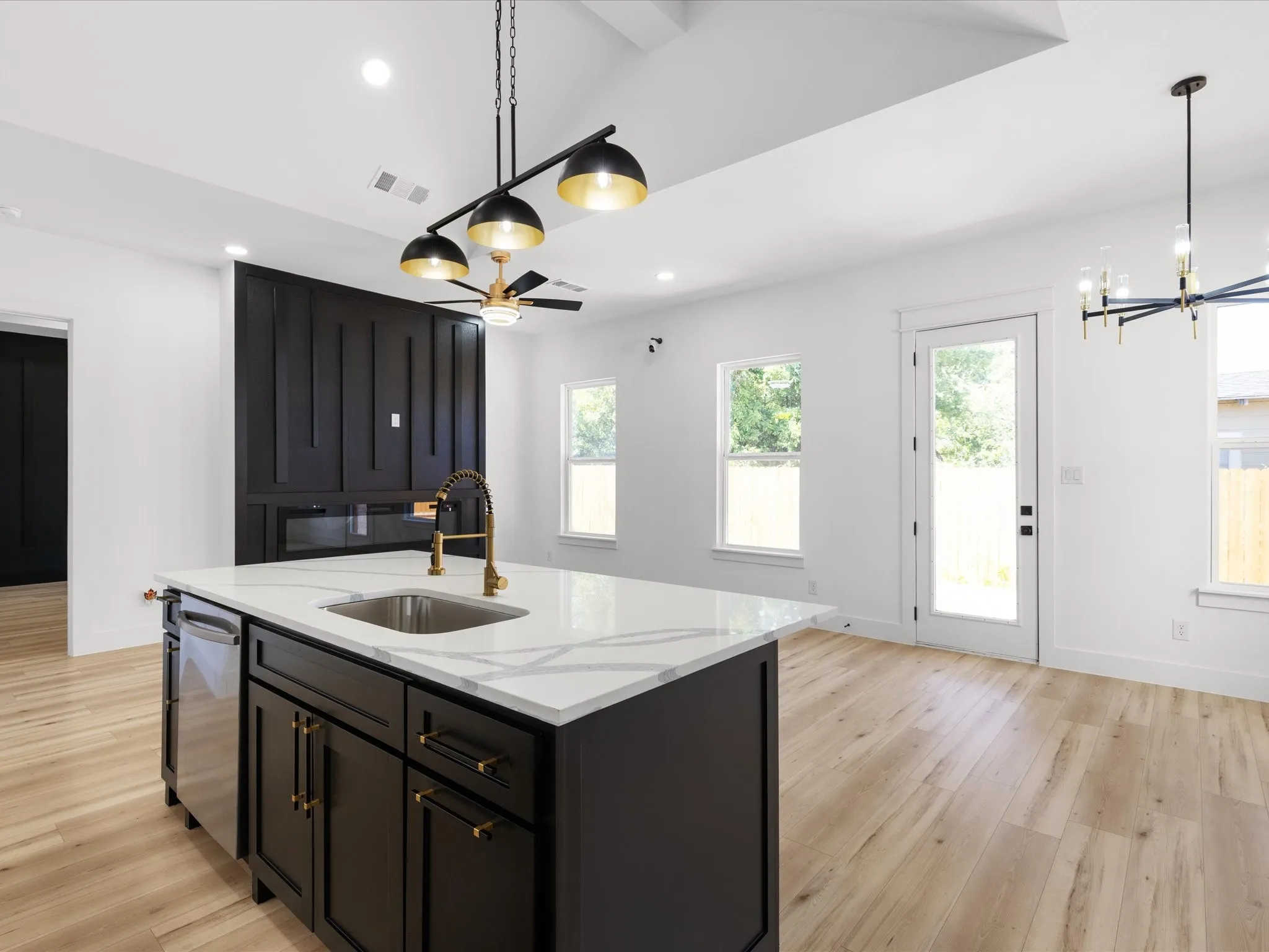 Kitchen island featuring a stainless steel sink, gold-finish faucet, and white countertop