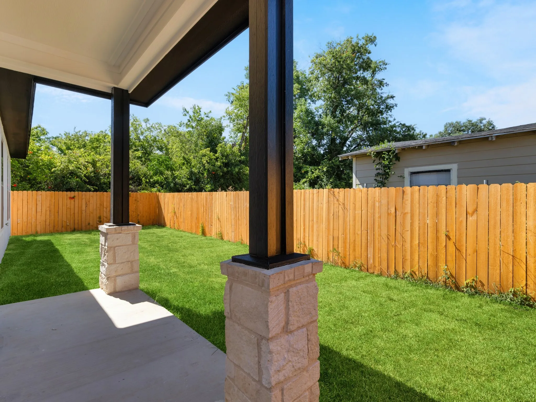 Covered patio featuring a concrete slab and stone-clad support columns
