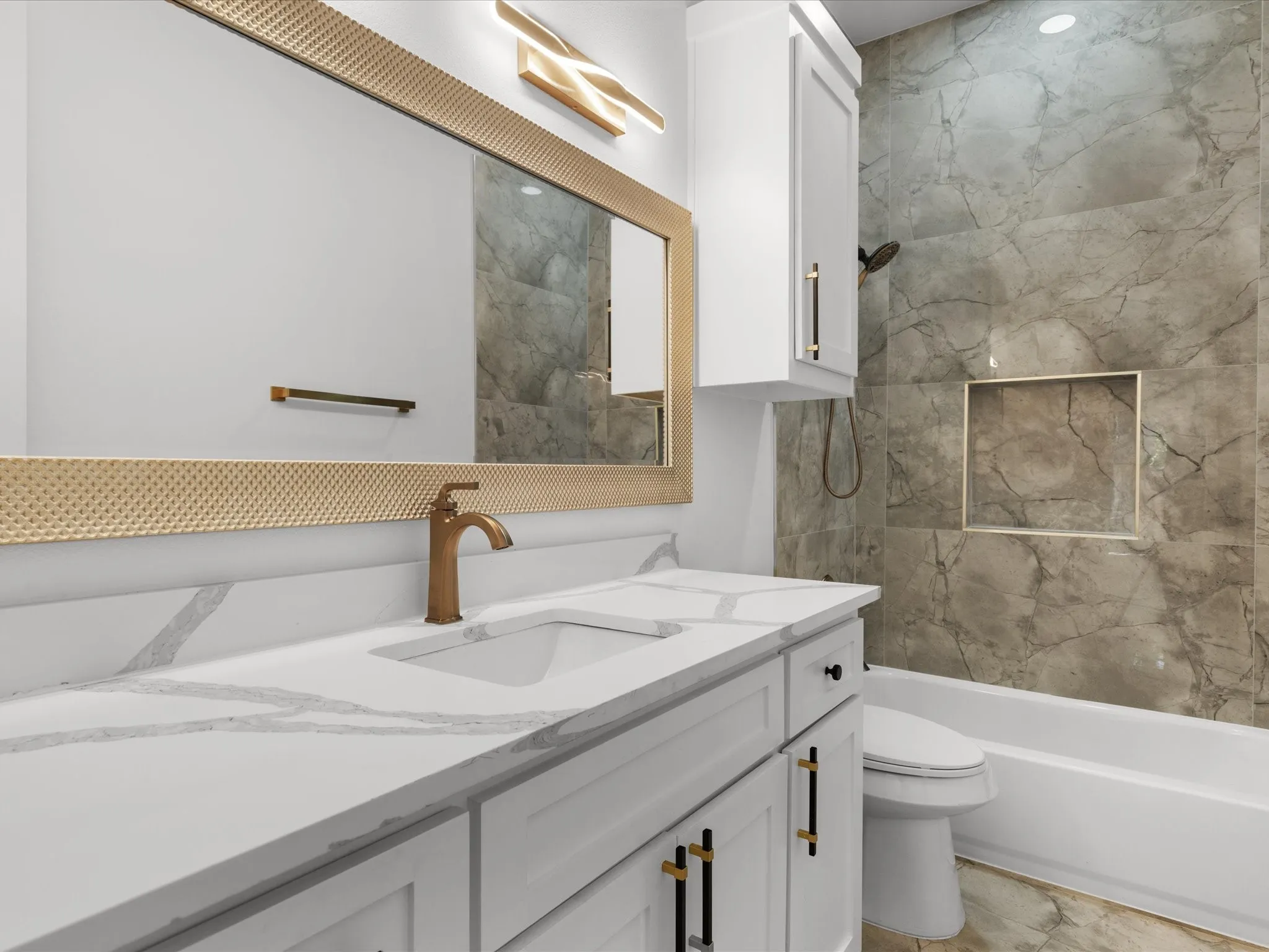 Bathroom vanity featuring a single basin, bronze-finish faucet, and white countertop with veining