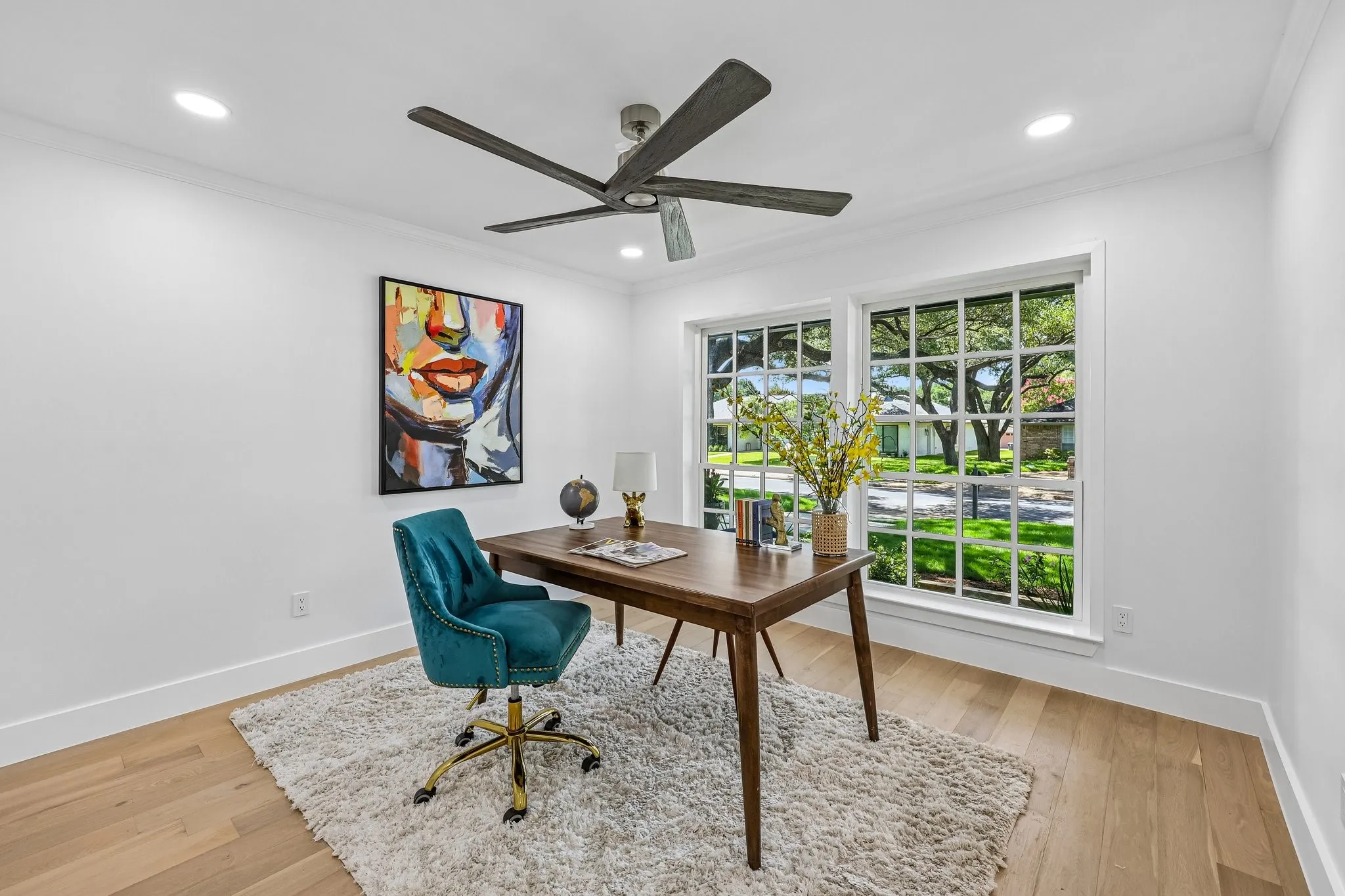Bright room featuring two large grid-pattern windows, wood-finish flooring, recessed lighting, and a ceiling fan with dark blades