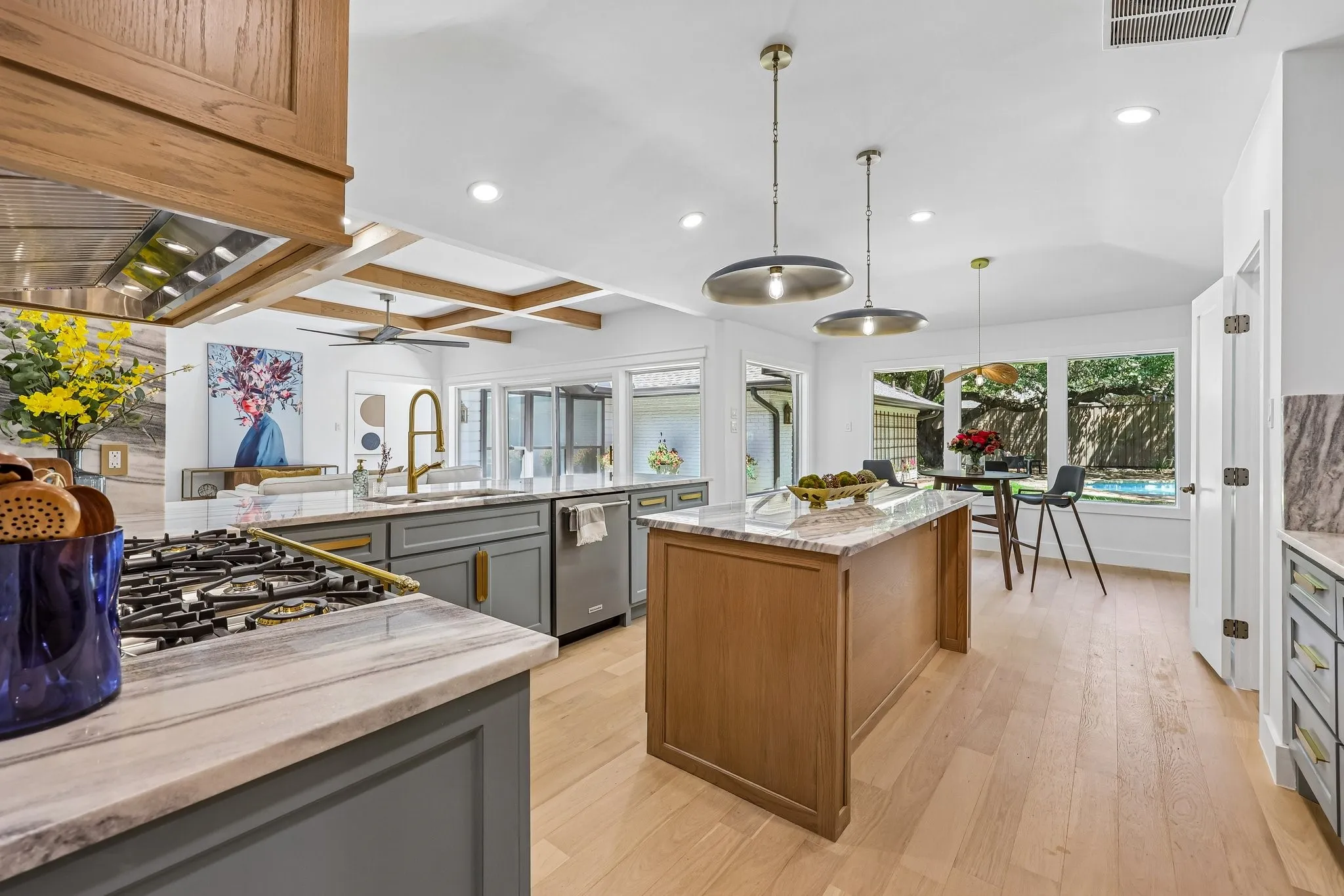 Open-concept kitchen featuring dual islands with stone countertops, gray shaker-style cabinetry, and integrated stainless steel appliances