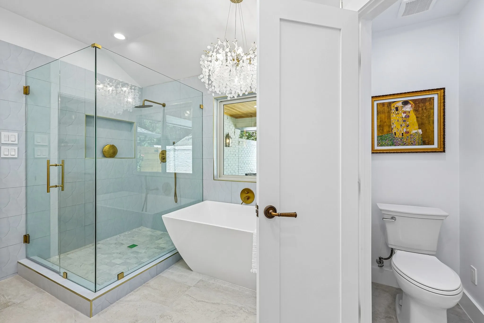 Contemporary bathroom featuring a frameless glass shower enclosure, a freestanding soaking tub, a decorative chandelier, a window with privacy glass, and gray tile flooring