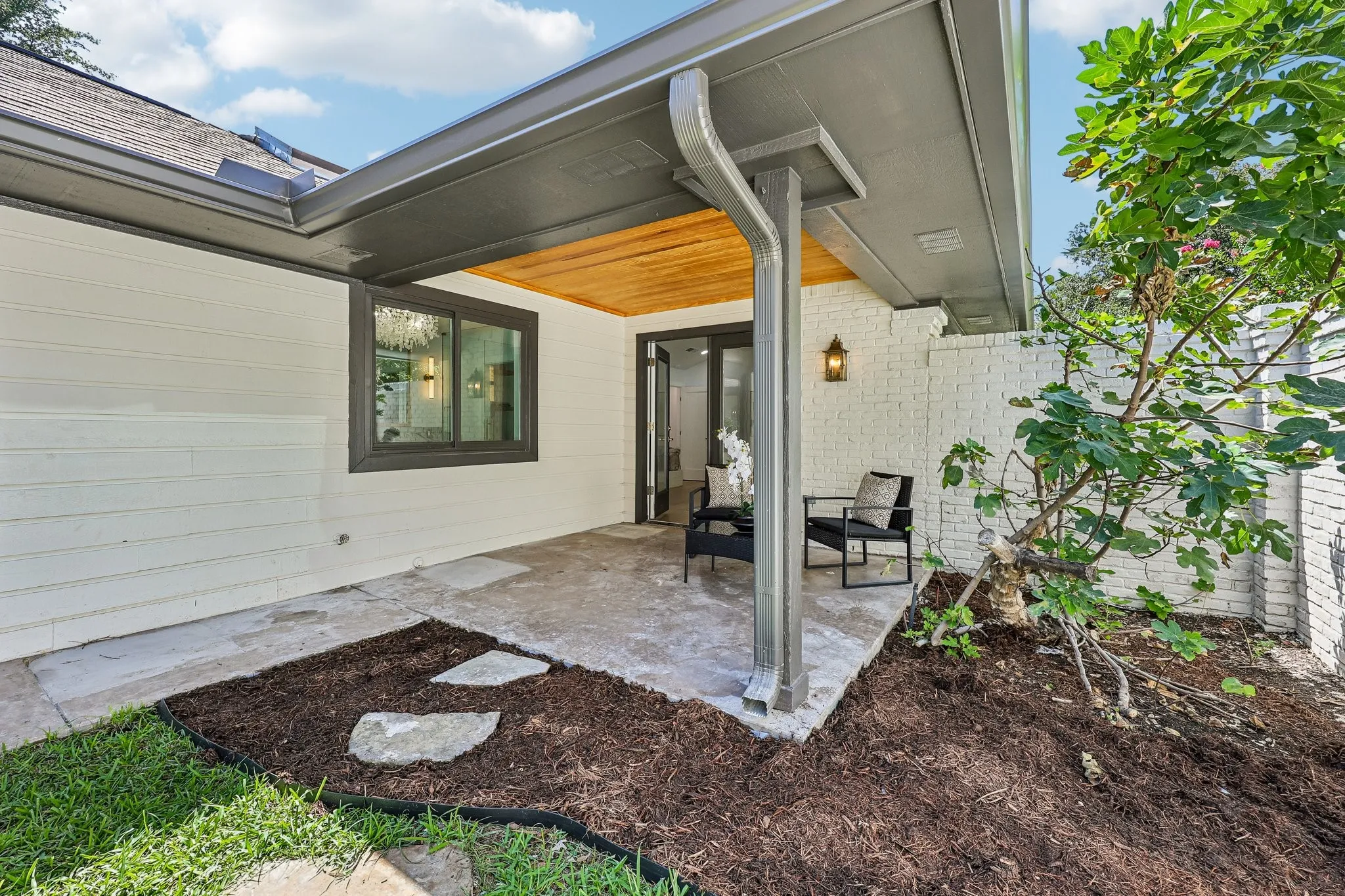 Covered patio featuring a wood-finish ceiling, a white brick accent wall, and a concrete patio surface