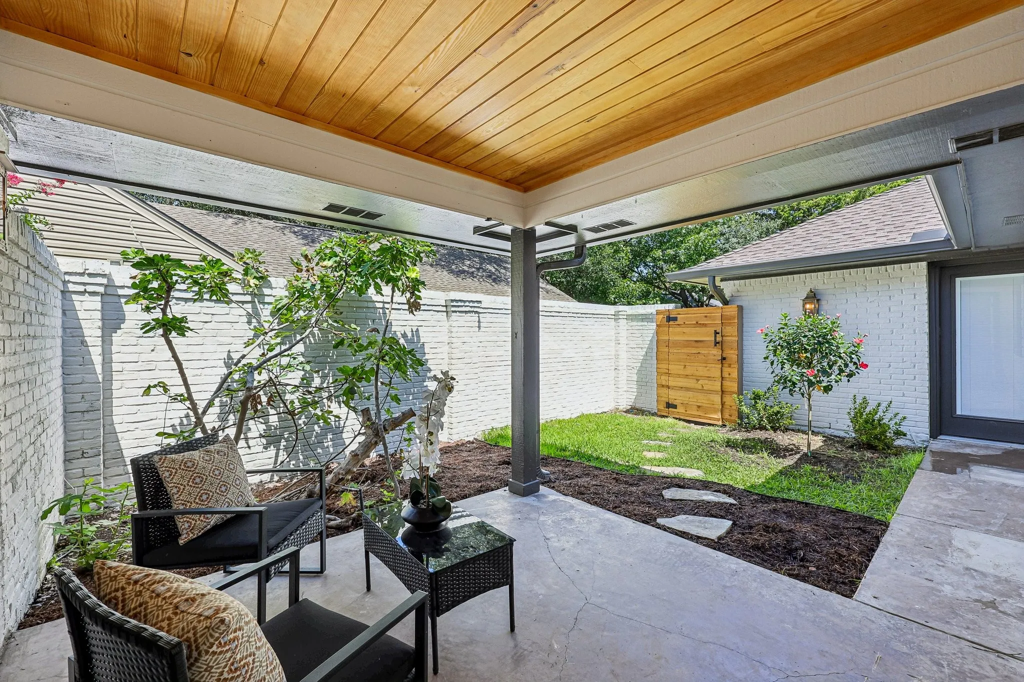 Covered patio featuring a wood-finish ceiling, concrete flooring, and a white brick privacy wall