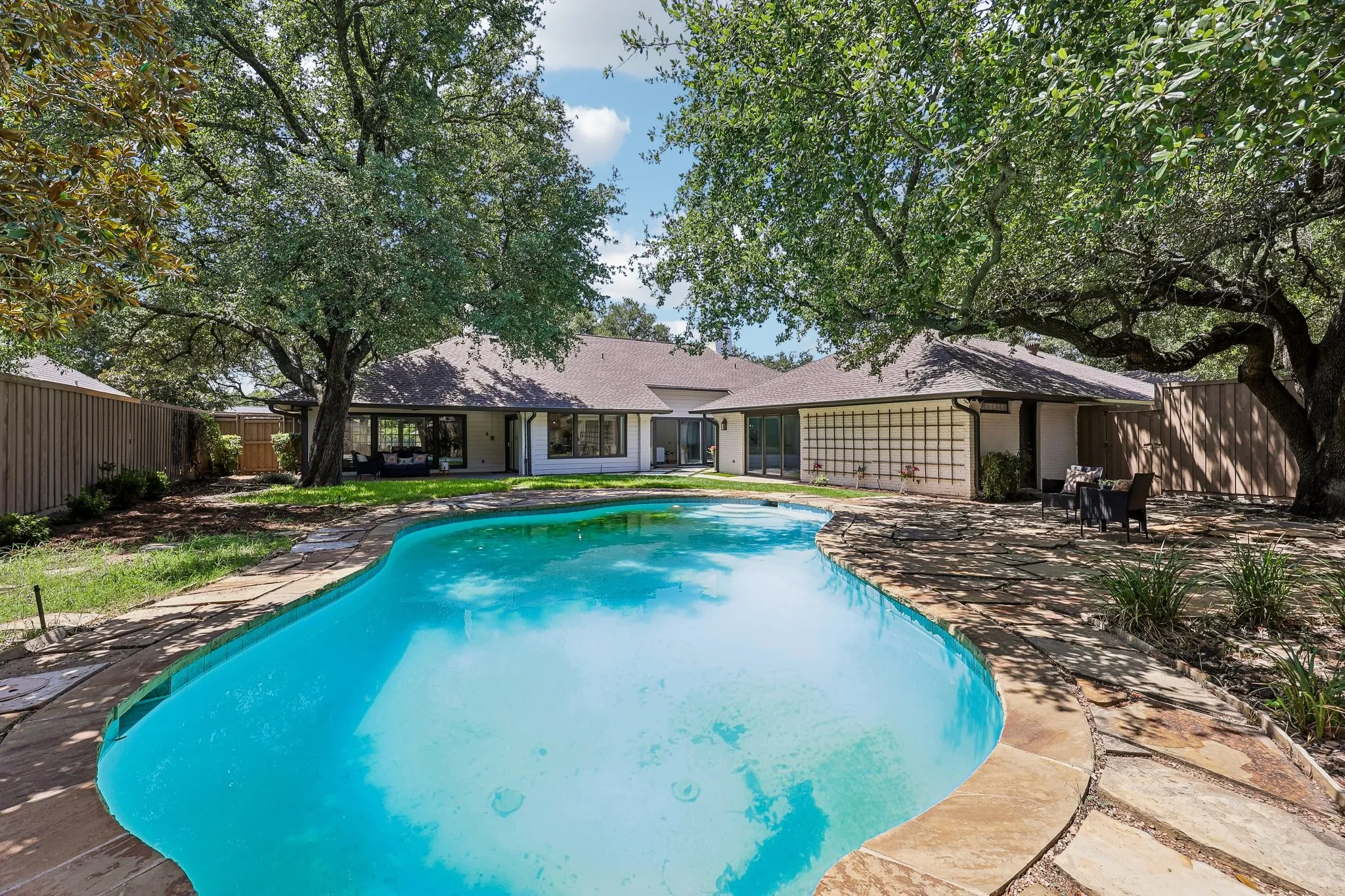 Freeform swimming pool with natural stone coping and surrounding patio