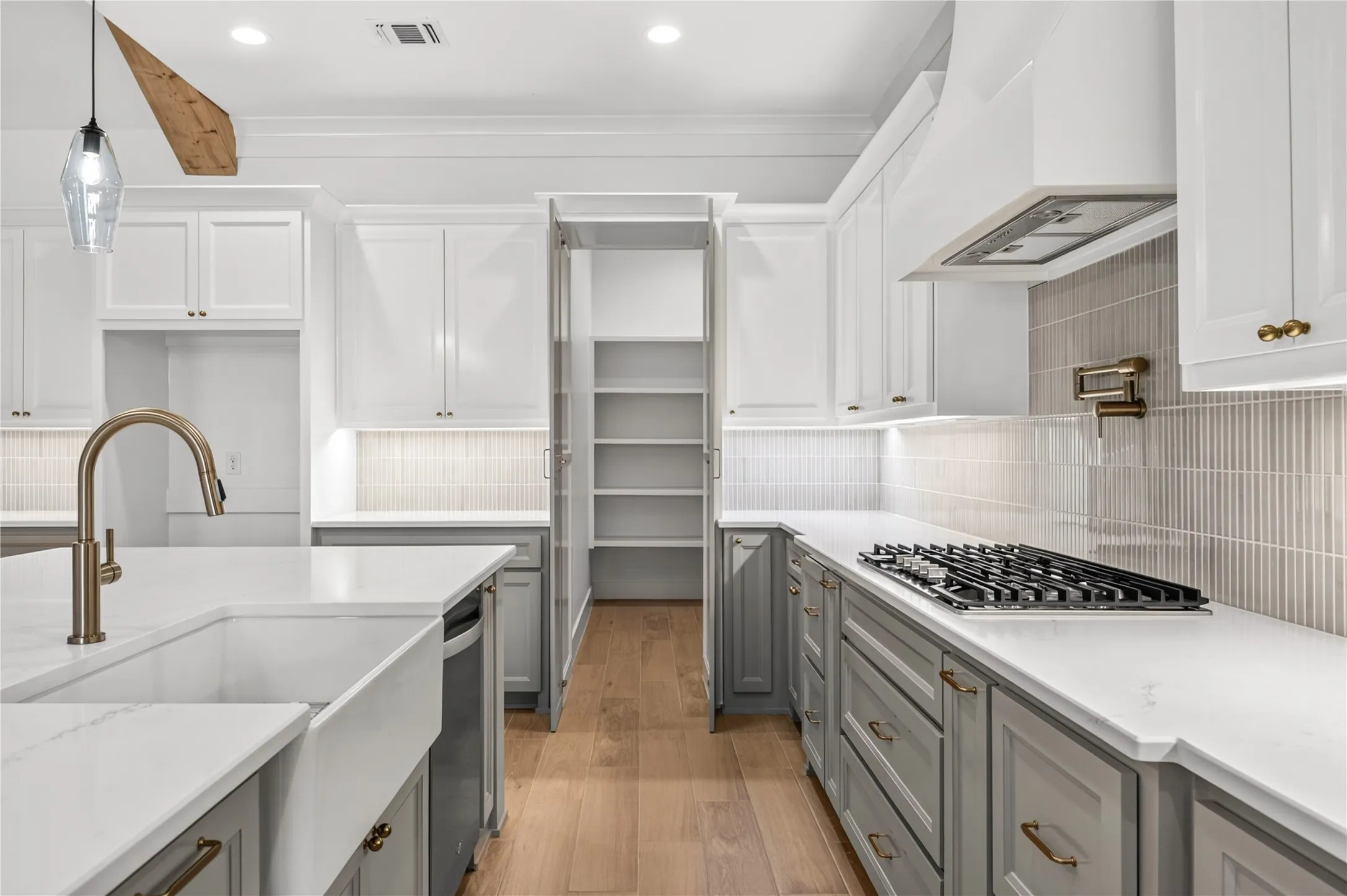 Contemporary kitchen featuring a gas range, farmhouse sink with gooseneck faucet, light wood-finish flooring, white countertops, and a tiled backsplash
