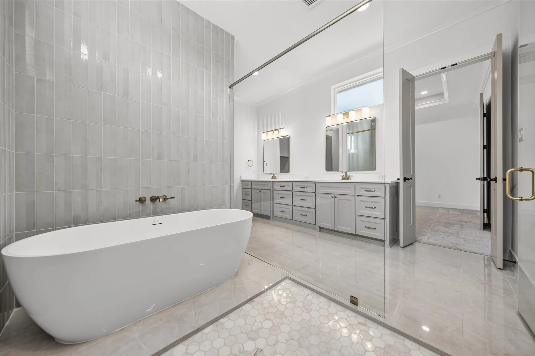 Freestanding soaking tub with wall-mounted bronze fixtures set against a tiled accent wall