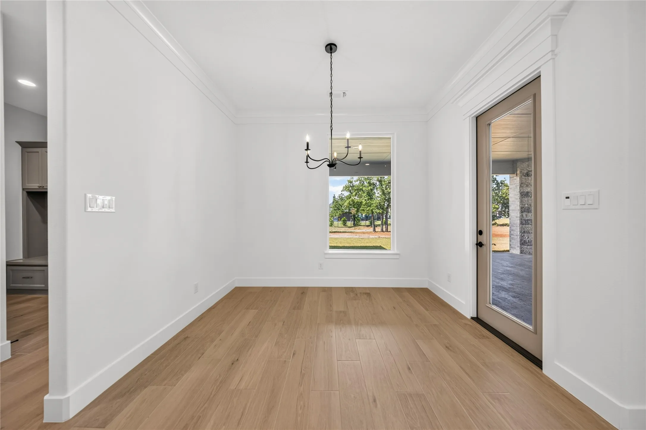 Spacious room with wood-finish flooring, crisp white walls, and crown molding