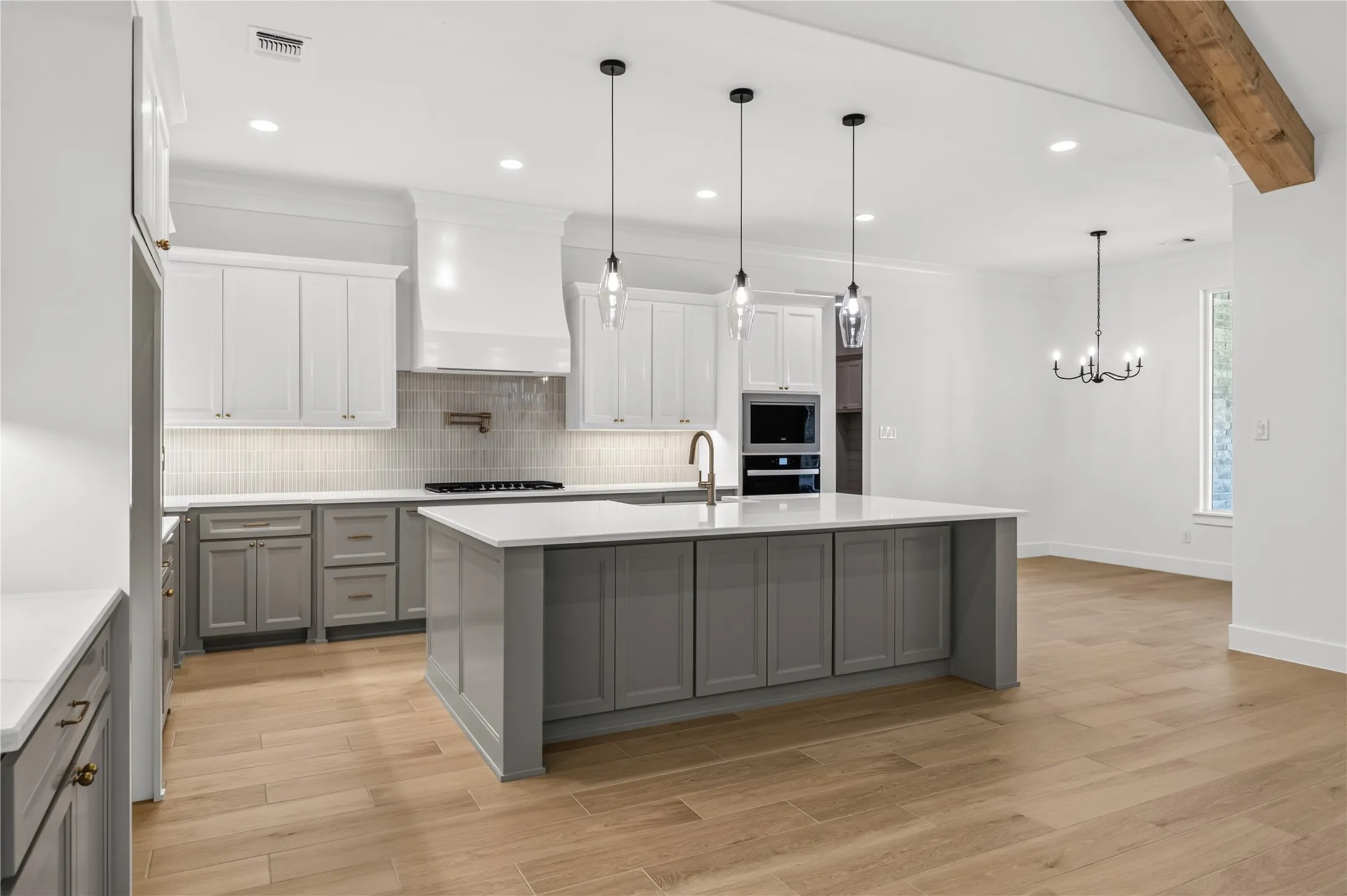 Open-concept kitchen featuring a large central island, light wood-finish flooring, and white countertops